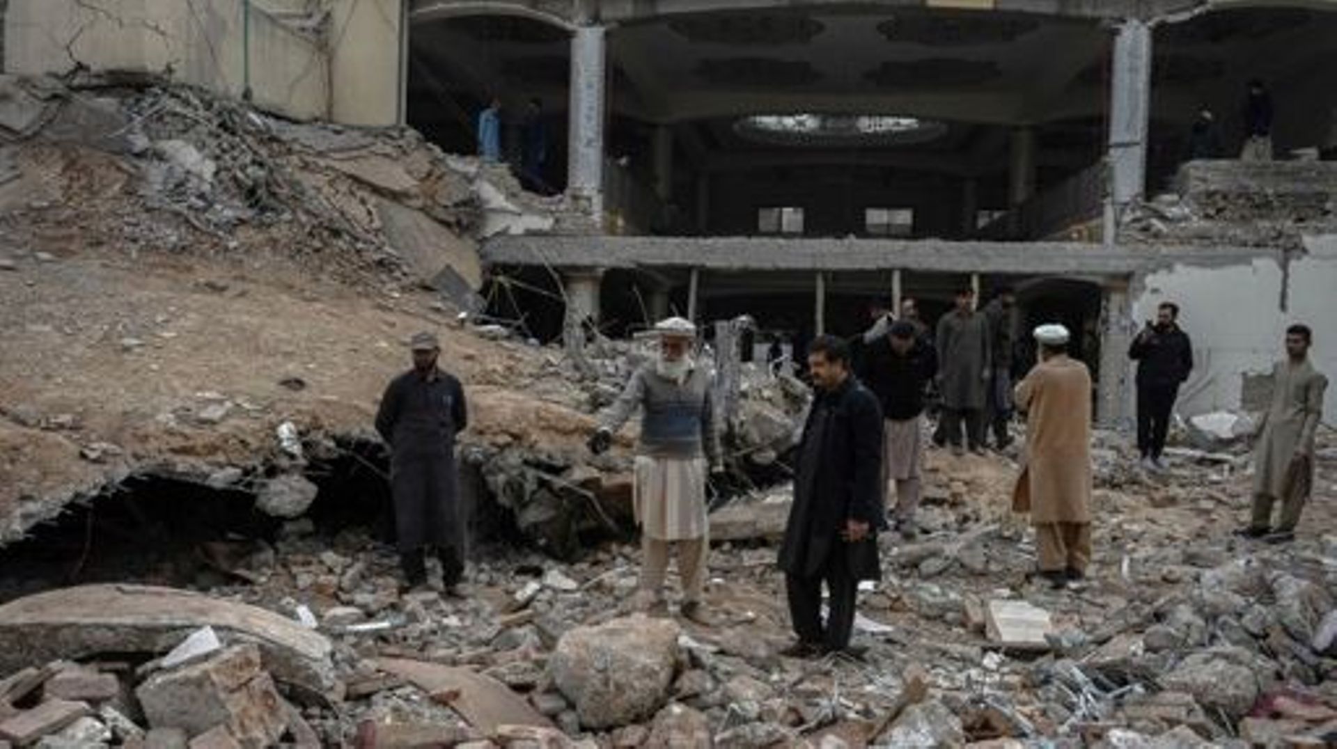 Plain-clothed policemen inspect the site as they gather over the rubble of a damaged mosque following January's 30 suicide blast inside the police headquarters in Peshawar on February 1, 2023. A suicide blast at a mosque inside a Pakistan police headquart