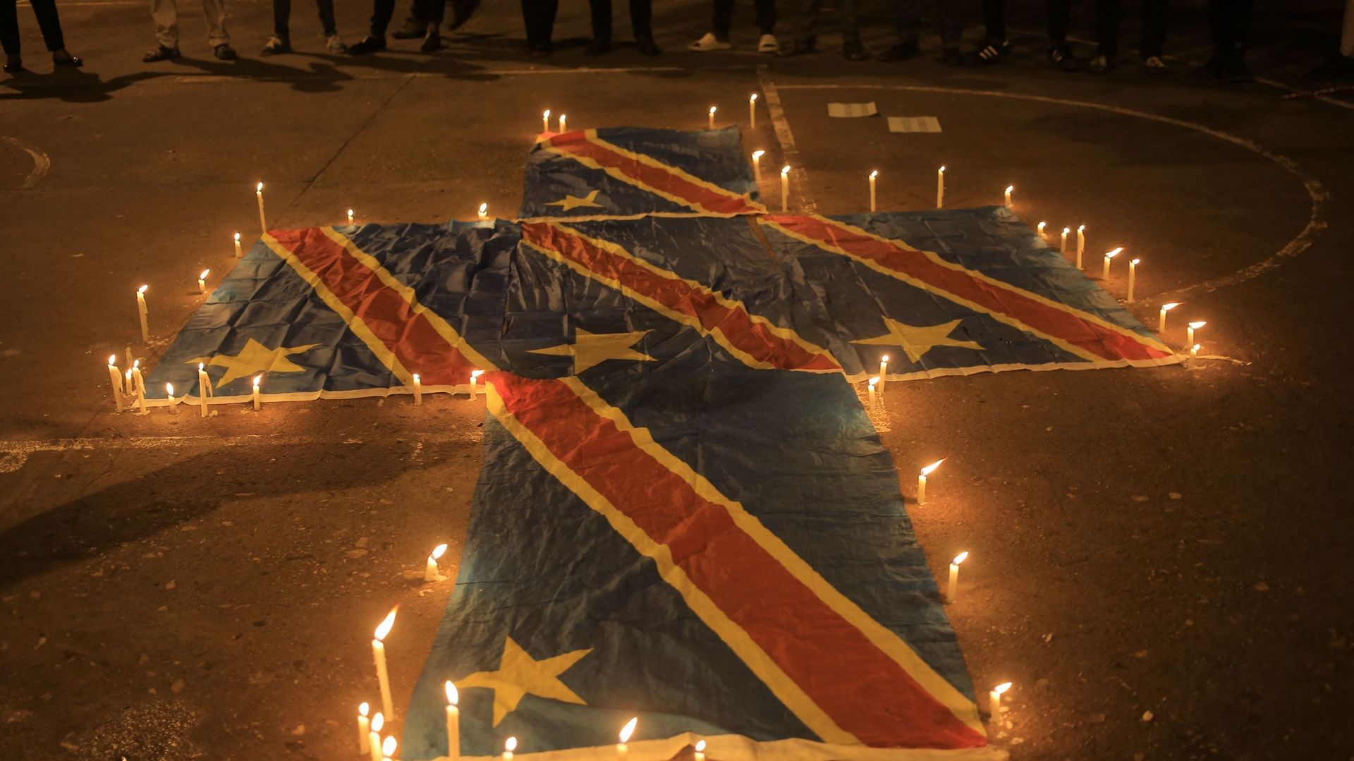 Des drapeaux de la République démocratique du Congo sont entourés de bougies à Beni, le 7 décembre 2022, lors d’une veillée de prière en mémoire des victimes des troubles en cours dans l’est du pays. Au moins 131 civils ont été tués par les rebelles du M2