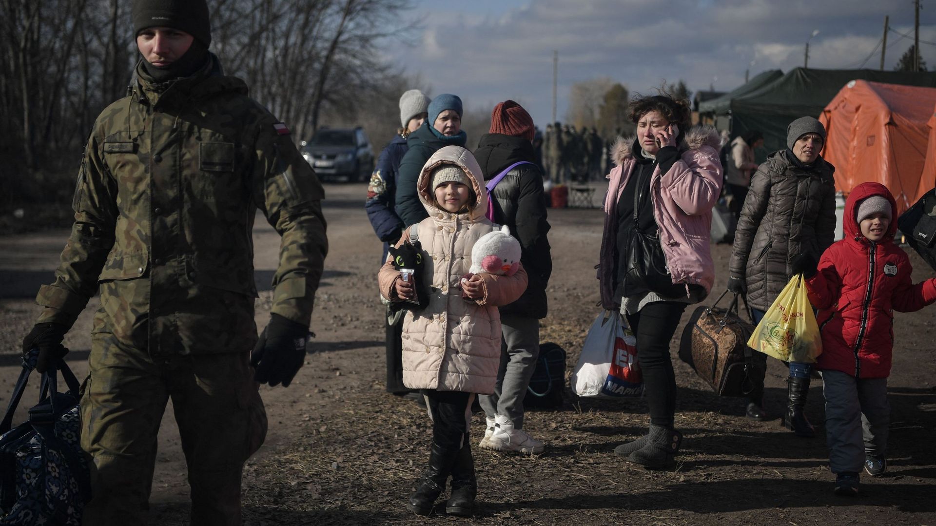 Un soldat polonais aide des familles à porter leurs affaires après avoir traversé la frontière ukraino-polonaise au poste frontière de Medyka, dans le sud-est de la Pologne, le 10 mars 2022.