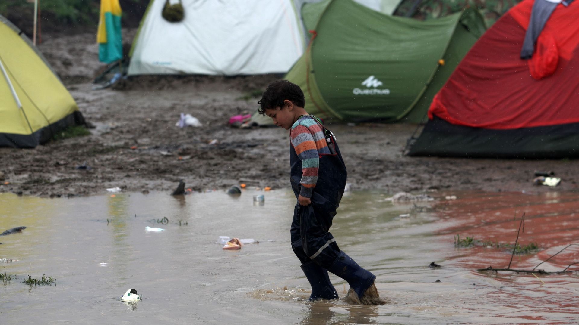 Un enfant marche dans une flaque boueuse dans un camp de fortune installé à la frontière greco-macédonienne, près du village d'Idomeni