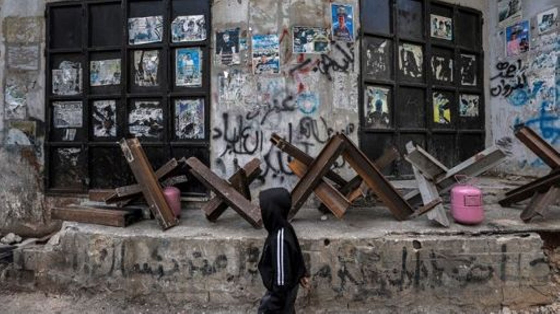 A boy walks past anti-vehicle steel obstacles placed outside closed shops in the Jenin camp for Palestinian refugees in the occupied West Bank on March 8, 2023 during a Palestinian general strike called in protest against the Israeli army raid there the p