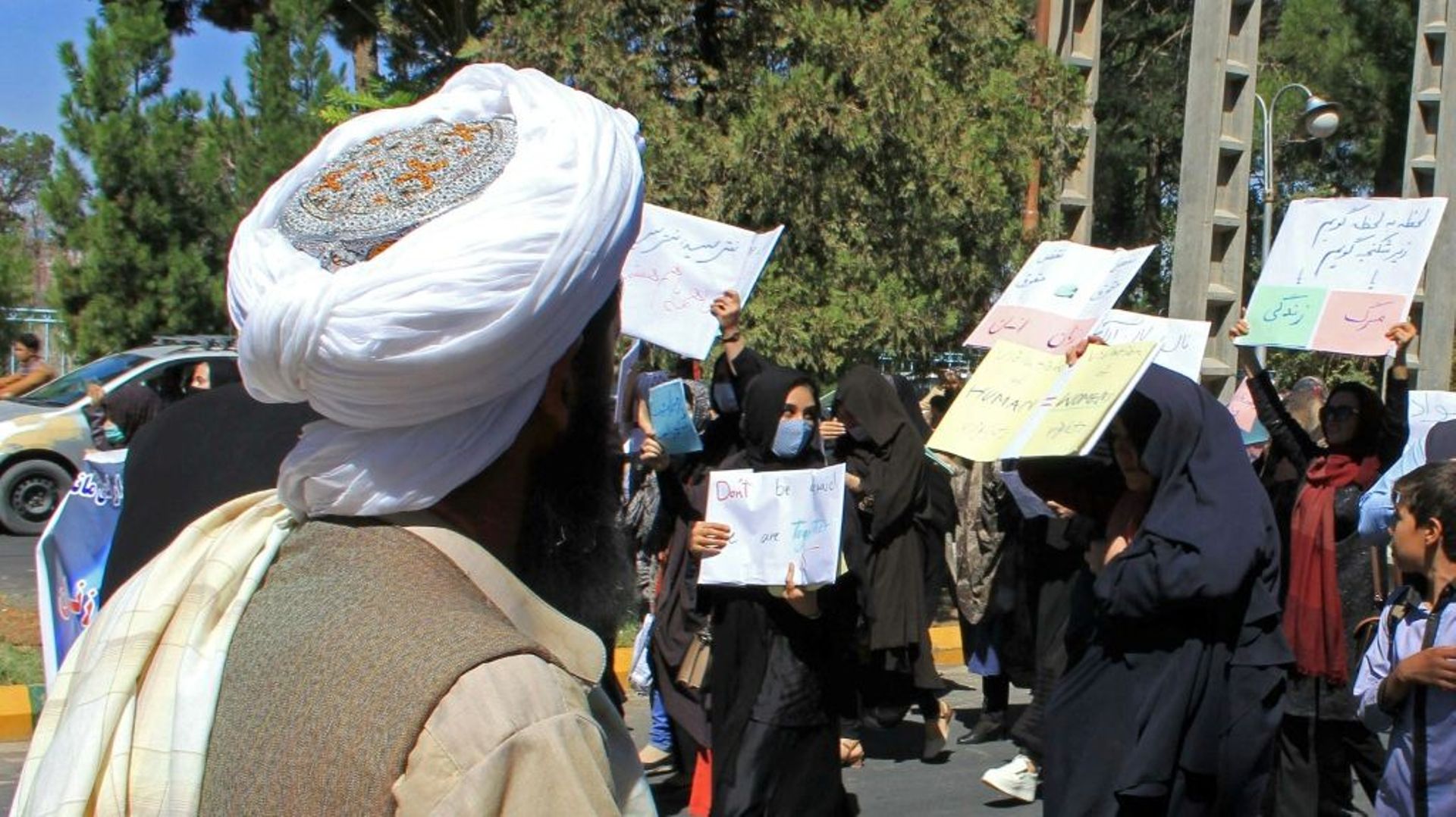Un taliban regarde des femmes manifestant pour leurs droits à Hérat, dans l'ouest de l'Afghanistan.