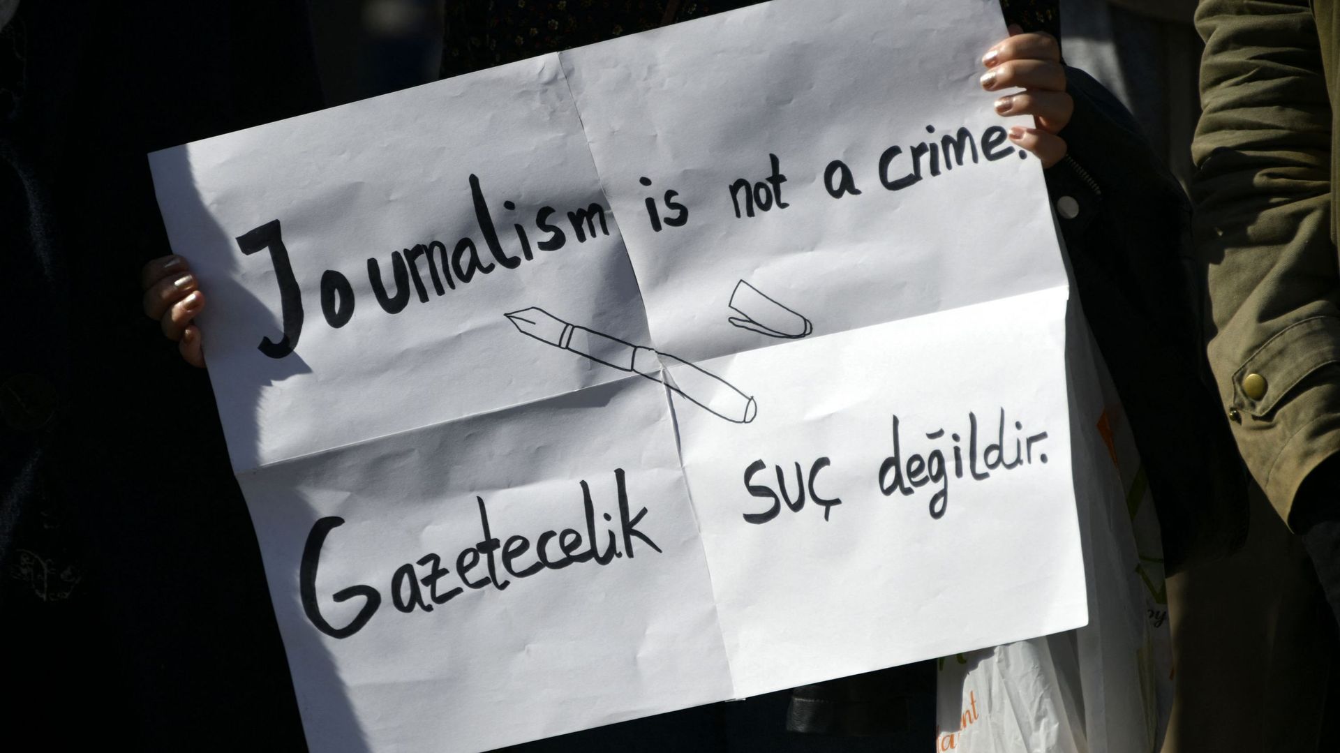 Un manifestant tient une pancarte sur laquelle on peut lire "Le journalisme n'est pas un crime", lors d'une manifestation intitulée "Erdogan n'est pas le bienvenu" en Allemagne