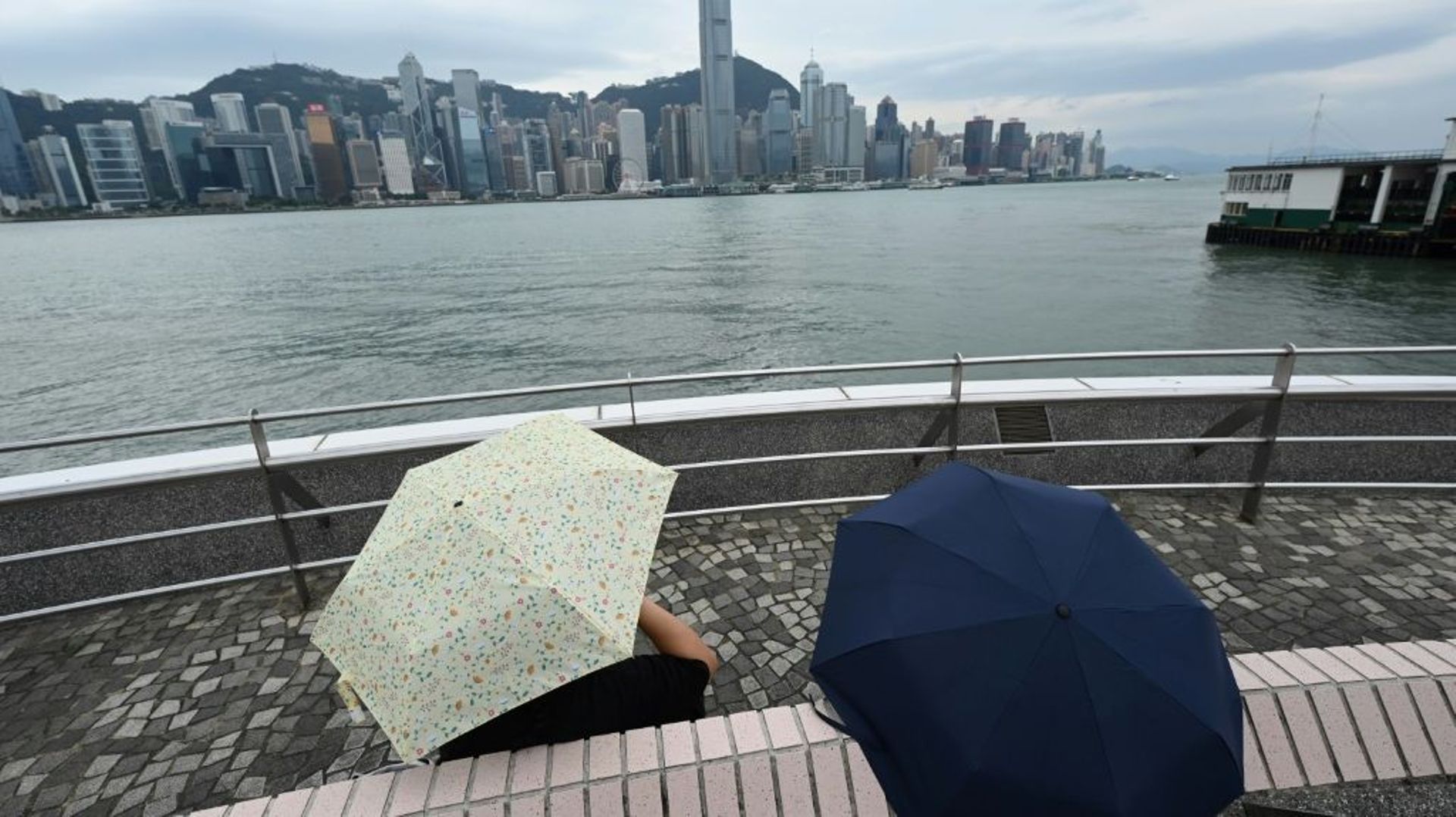 Des personnes regardent les gratte-ciel de Hong Kong depuis le port avant l’arrivée d’un deuxième typhon en moins d’une semaine, le 12 octobre 2021.