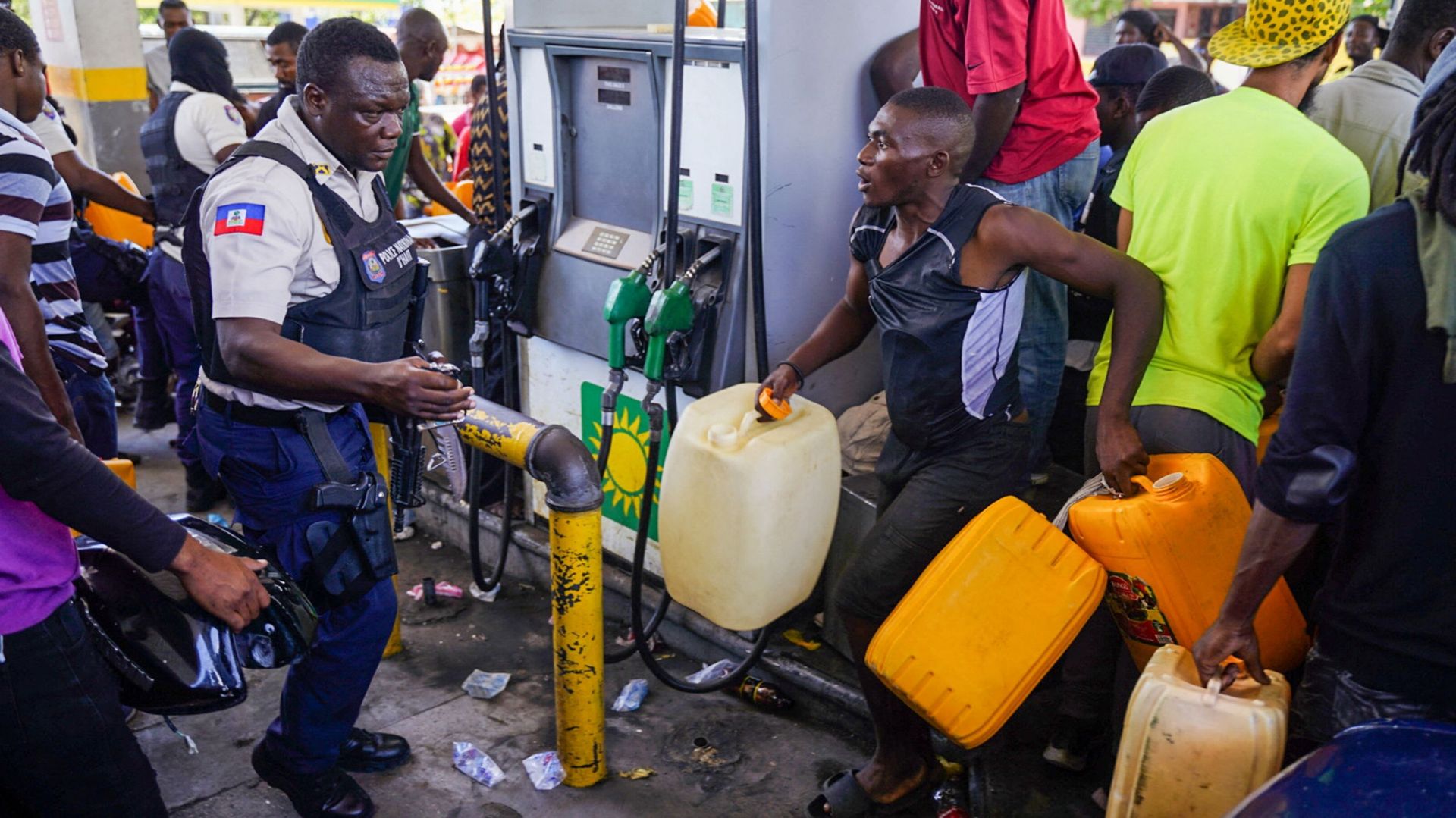 Un policier haïtien s’affronte dans une file d’attente pour récupérer de l’essence dans une station-service de Port-au-Prince le 15 juillet 2022.