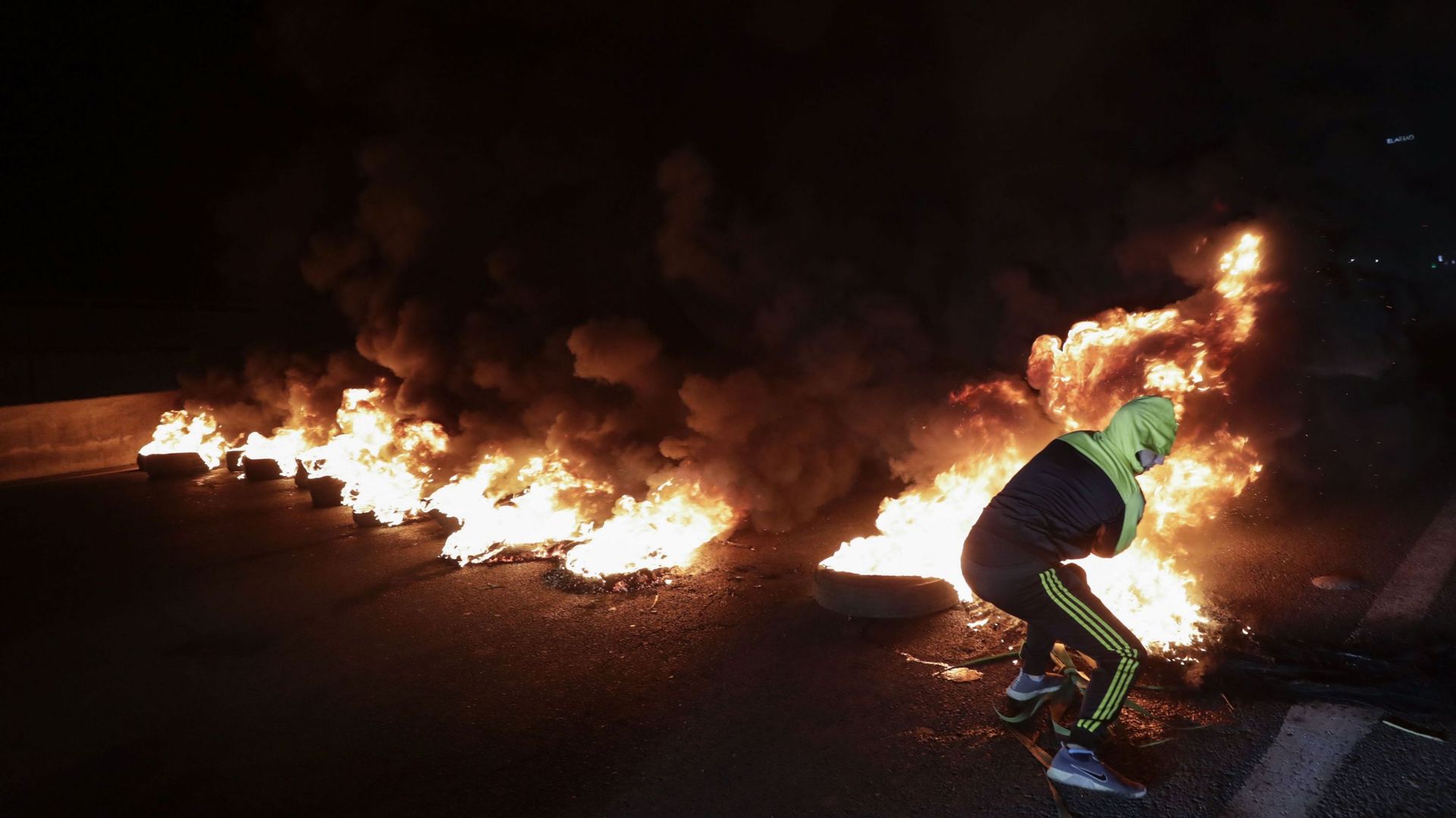 Un manifestant anti-gouvernement brûle des pneus pour bloquer une autoroute dans la zone de Dbayeh au nord de Beyrouth, la nuit du 26 au 27 avril 2020.