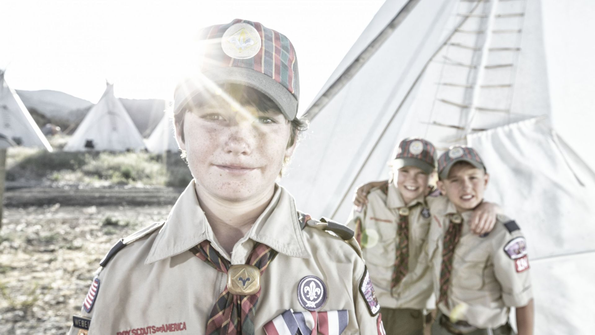 Three young, Weblo Boy Scouts standing near a teepee at a camp in Colorado.