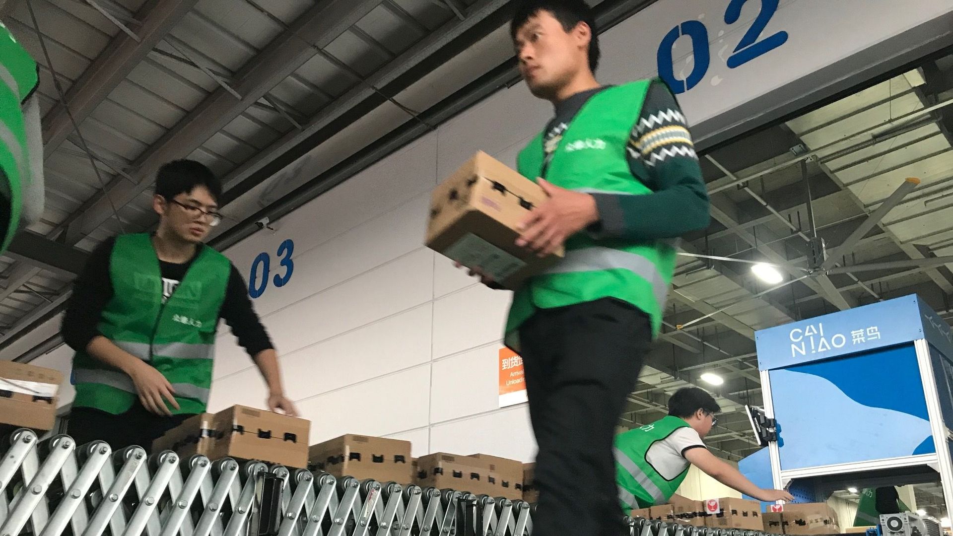 Des travailleurs chargent des camions avec des colis devant un entrepôt de Cainiao Smart Logistics dans le Xiasha Park de Hangzhou (Chine), le jour de la fête des célibataires, le 11 novembre 2019