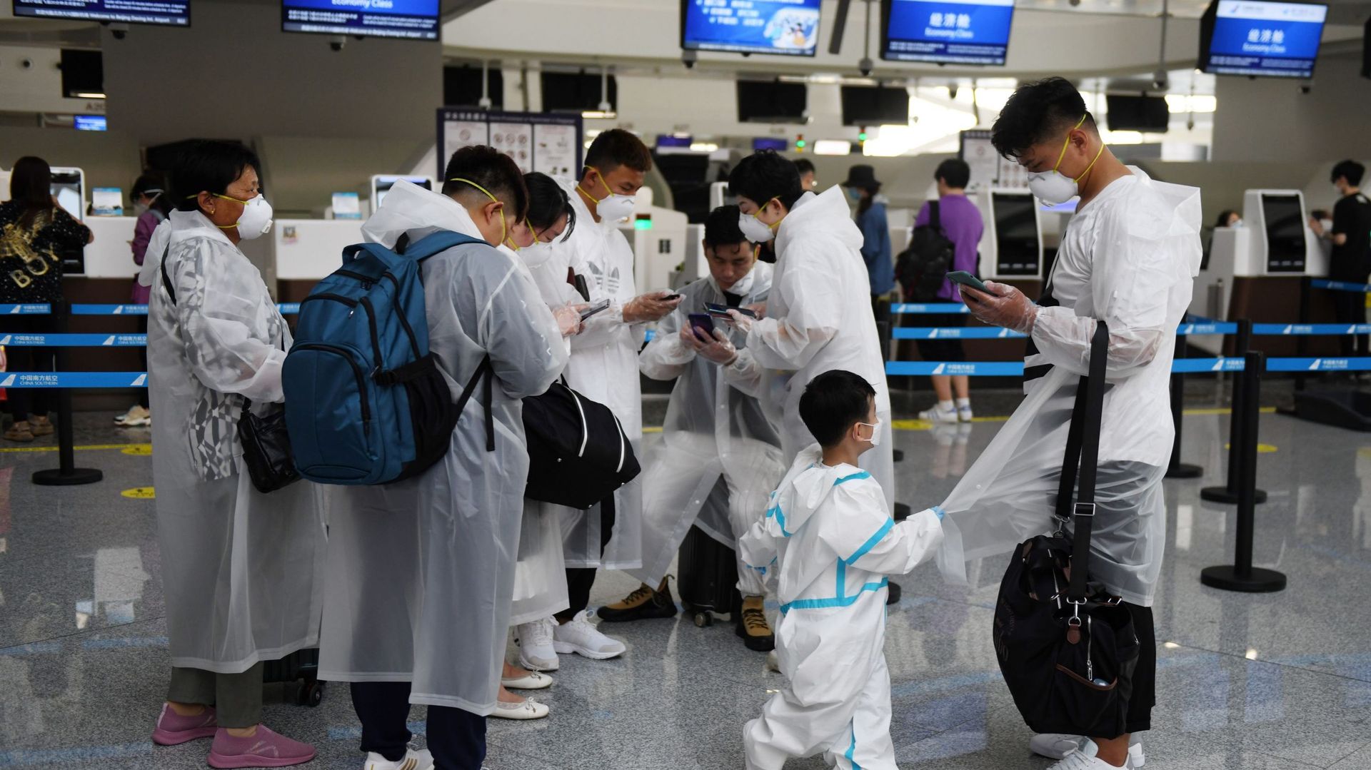 Des Chinois portent des vêtements de protection alors qu’ils attendent au comptoir d’enregistrement de l’aéroport de Pékin-Daxing à la veille d’une fête nationale de cinq jours le 30 avril 2020.