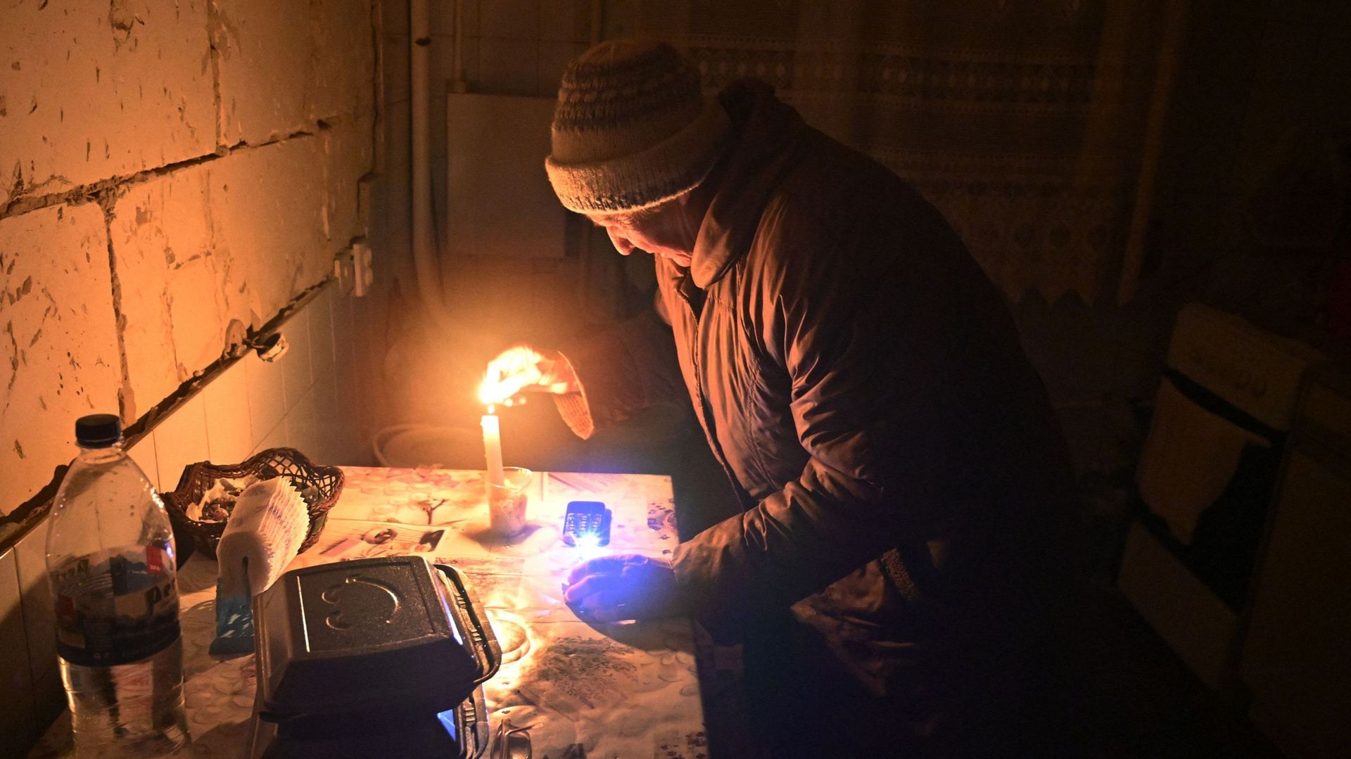 Une femme âgée allume une bougie dans son appartement dans un immeuble résidentiel, partiellement détruit à la suite des bombardements russes en février, lorsque la Russie a envahi l’Ukraine pour la première fois, dans le village de Gorenka, dans la régio