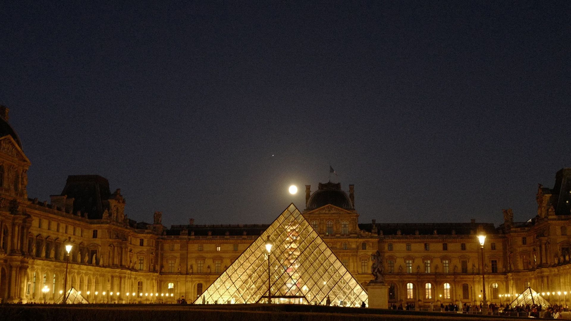 Une photo prise le 8 octobre 2022 montre la lune au-dessus de la Pyramide du Louvre, conçue par Ieoh Ming Pei, à Paris.