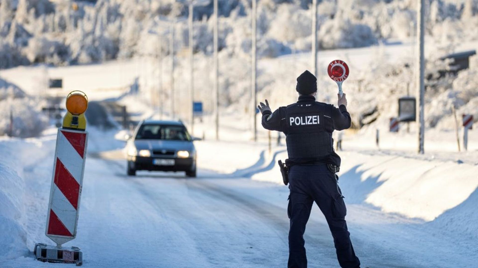 Un policier fédéral allemand arrête un véhicule pour un contrôle à un poste frontière avec l'Autriche le 14 février 2021 près de Zinnwald.