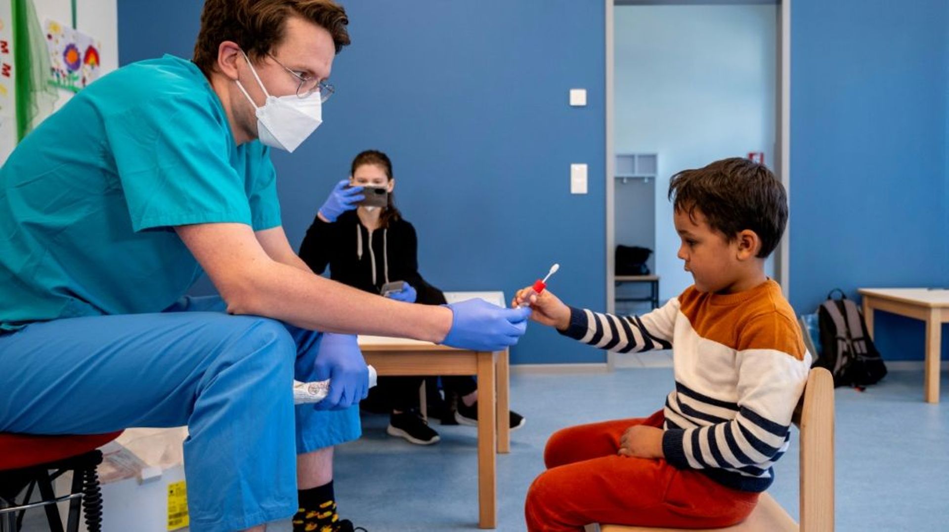 Un soignant tend une sucette à un jeune garçon pour le tester au Covid-19, dans un jardin d'enfants à Vienne, le 28 avril 2021