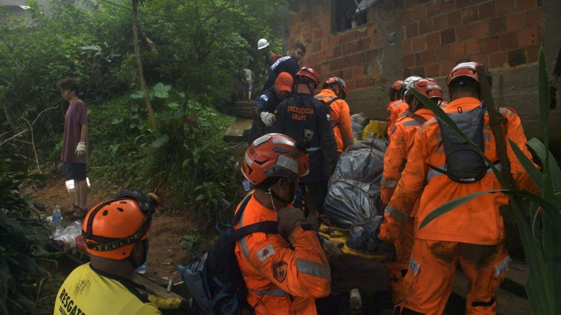 Des sauveteurs portent le corps d'une victime après des glissements de terrain causés par des pluies diluviennes, le 19 février 2022 à Petropolis, au Brésil