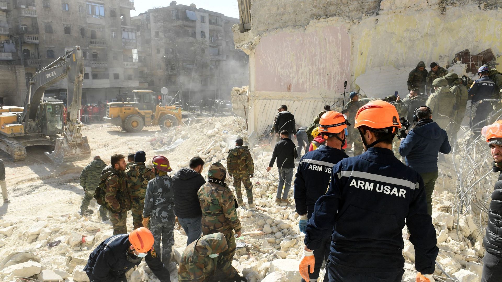 Des sauveteurs arméniens (casque orange) et des soldats syriens passent au crible les décombres d'un bâtiment effondré dans la ville d'Alep, au nord du pays, à la recherche de victimes et de survivants, quelques jours après le séisme meurtrier qui a frapp