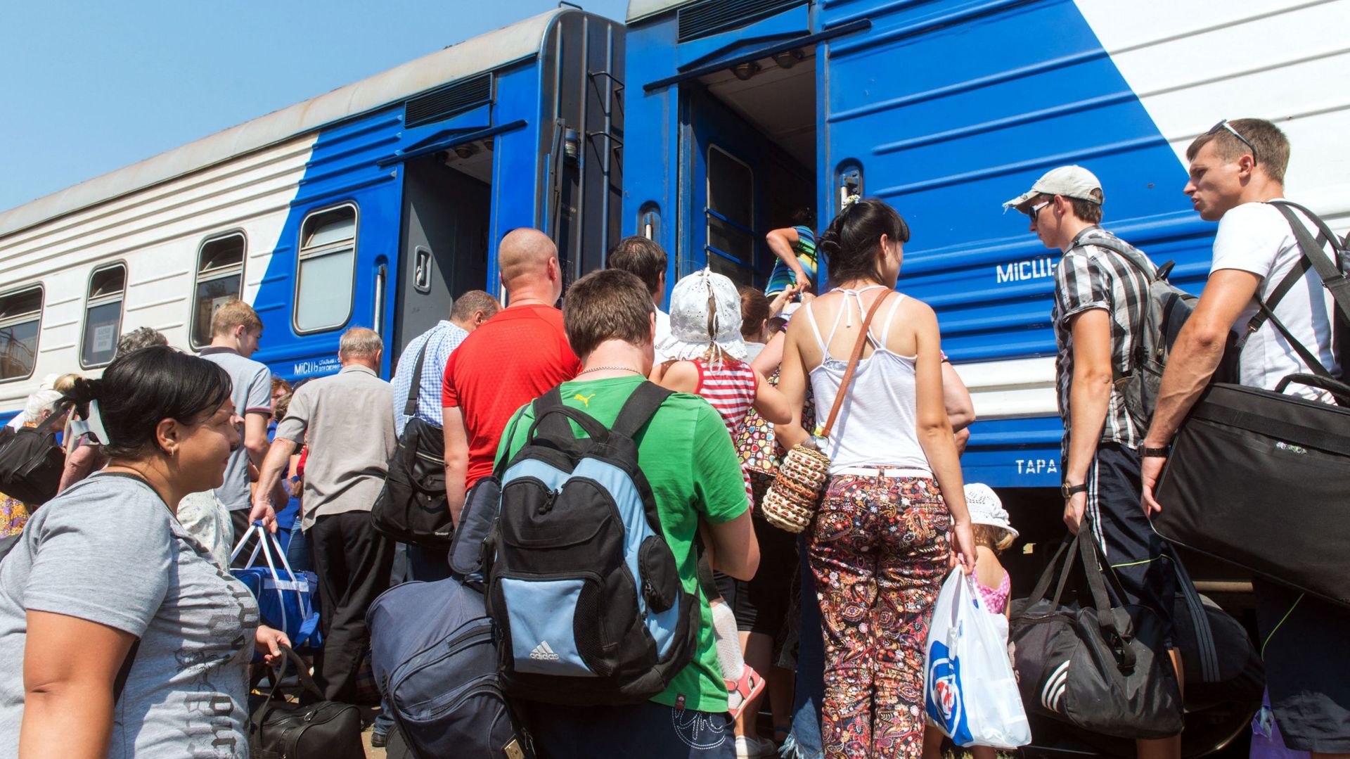 Des personnes montent à bord d’un train spécial pour quitter la petite ville de Svatovo, dans la région de Lugansk, dans l’est de l’Ukraine, le 12 août 2014.