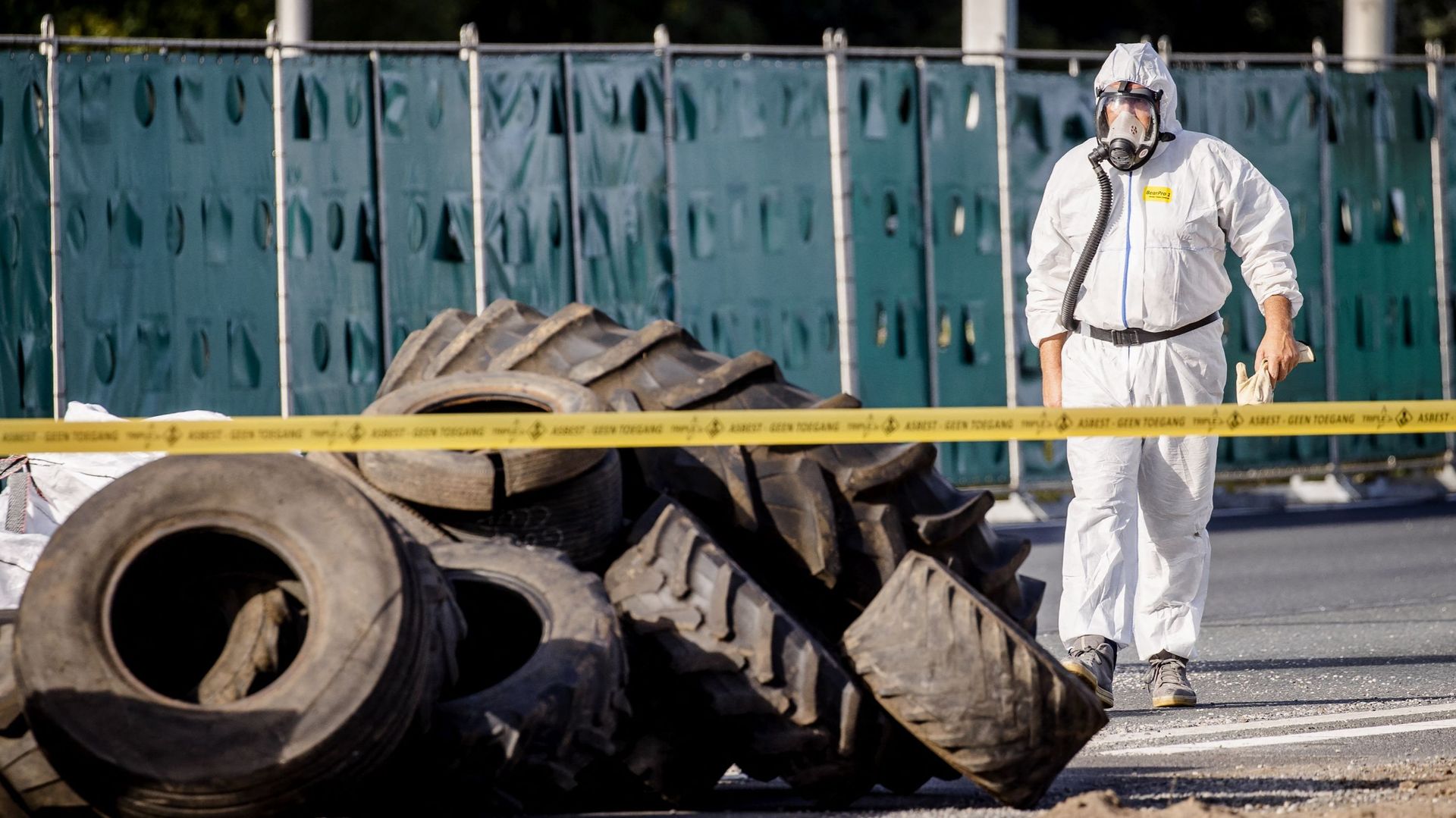 Un employé de société de nettoyage vient déblayer des déchets d’amiante et de pneus déposés par des agriculteurs en colère sur l’autoroute à Voorst, aux Pays-Bas.