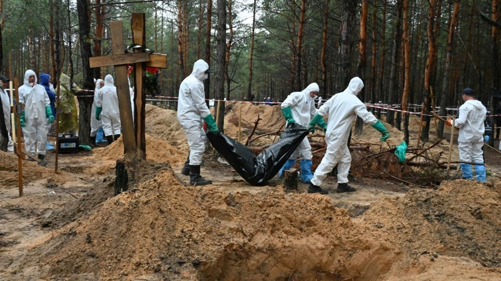Des enquêteurs dégagent un corps enveloppé dans un sac plastique près d’Izioum, dans l’est de l’Ukraine, le 23 septembre 2022