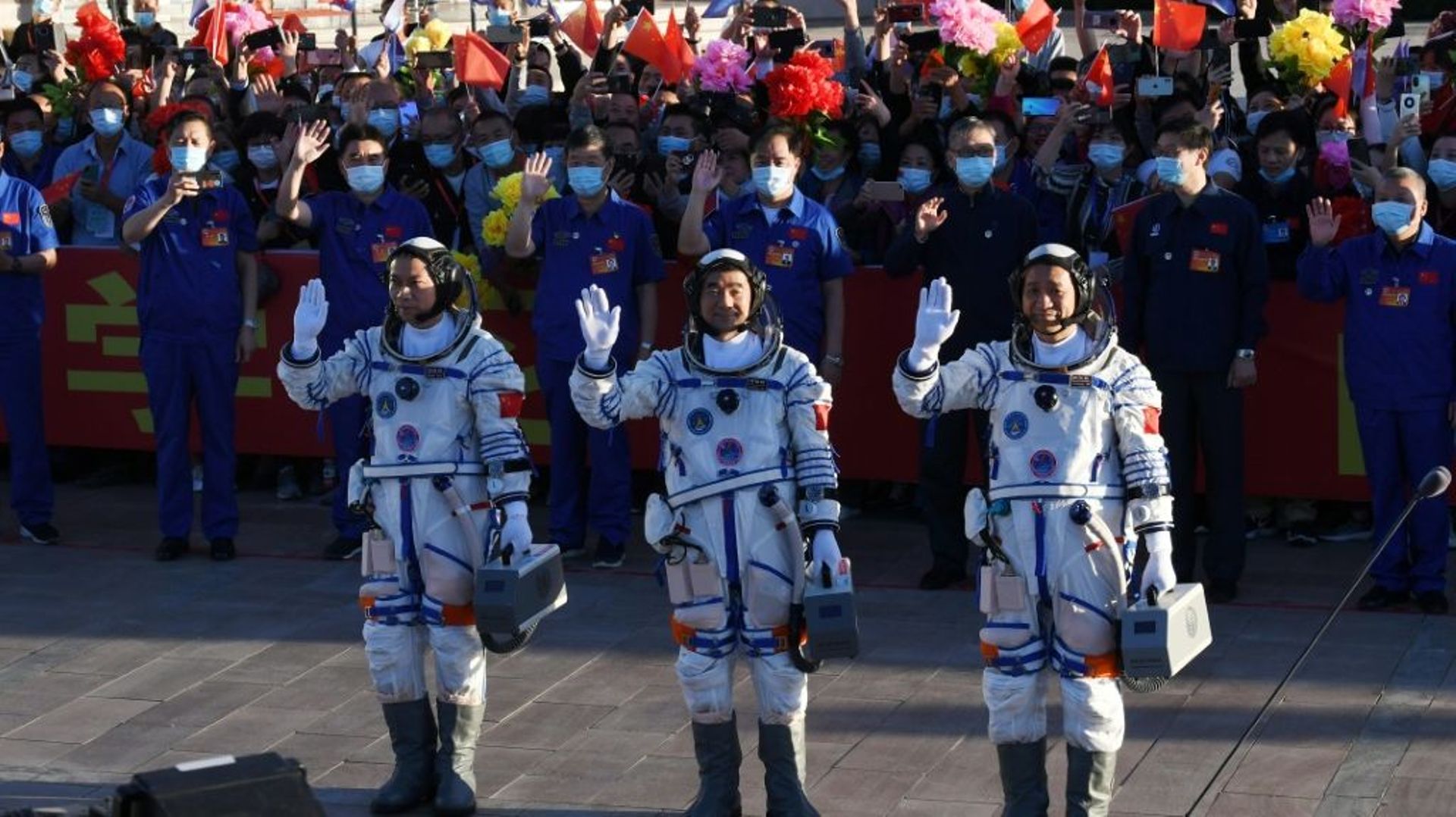 Les astronautes chinois Nie Haisheng (c), Liu Boming (d) et Tang Hongbo salue la foule avant leur décollage à bord de la fusée Longue-Marche 2F au Centre de lancement spatial de Jiuquan, le 17 juin 2021 en Chine