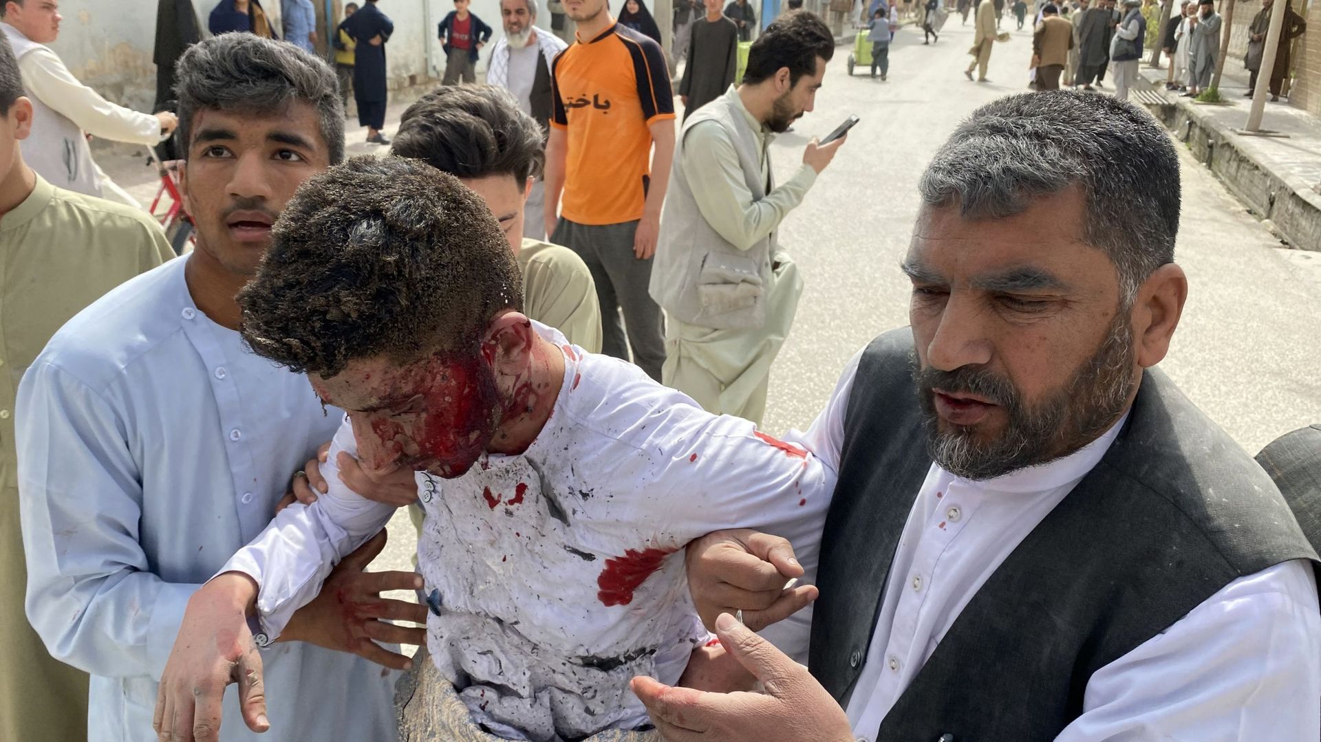 Un homme blessé est aidé par des hommes près du site d’un attentat à la bombe lors d’un événement commémorant les médias, à Mazar-i-Sharif, le 11 mars 2023.