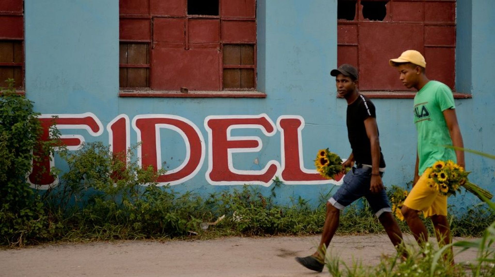 Des Cubains marchent face au nom Fidel inscrit sur un mur, à La Havane le 21 novembre 2019