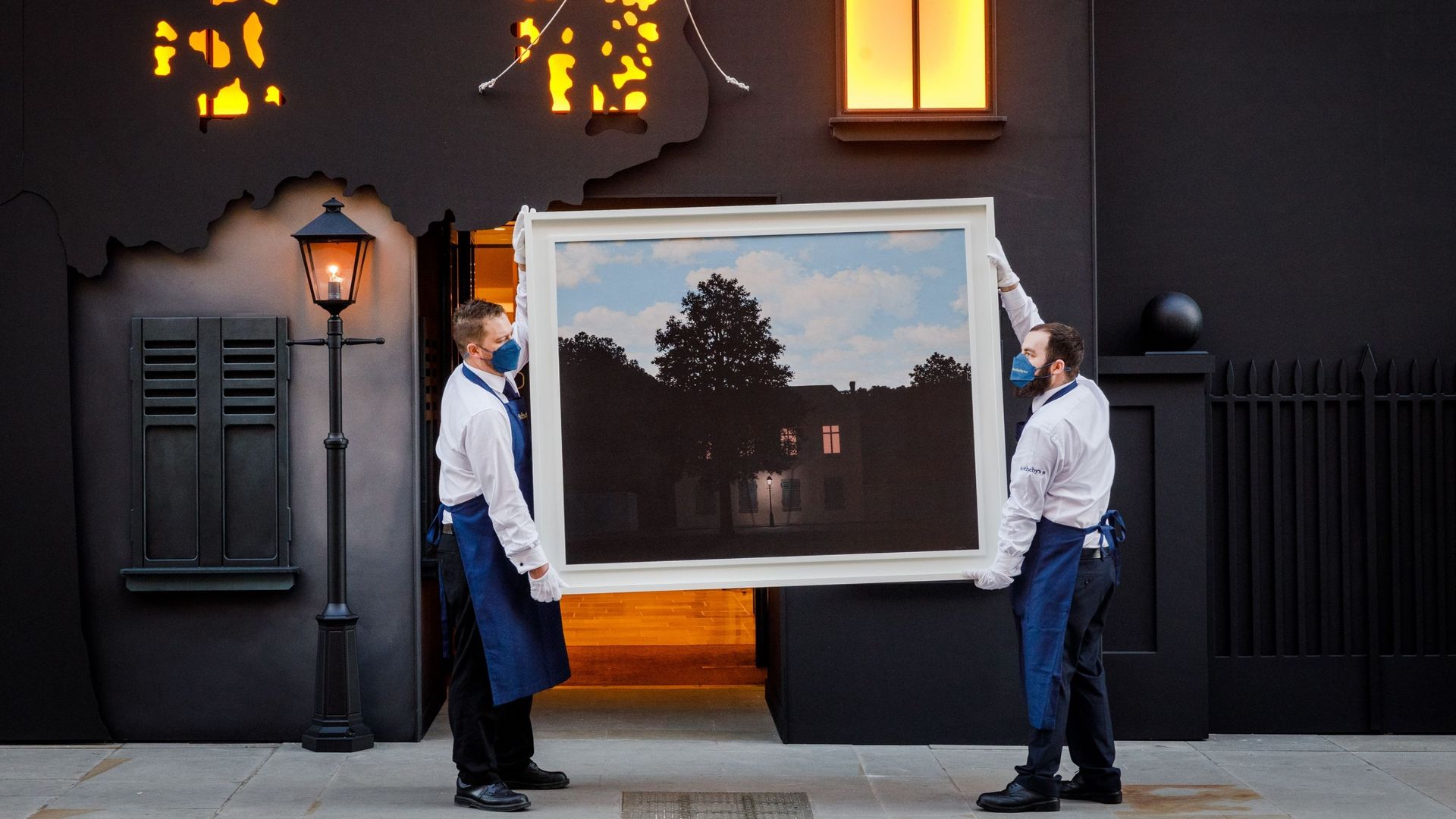 Du personne de Sotheby's tient le chef-d'œuvre de René Magritte, L'empire des lumières, devant l'entrée de la maison de vente aux enchères New Bond Street chez Sotheby's le 23 février 2022 à Londres, en Angleterre. Le tableau est en vente ce mercredi 2 ma
