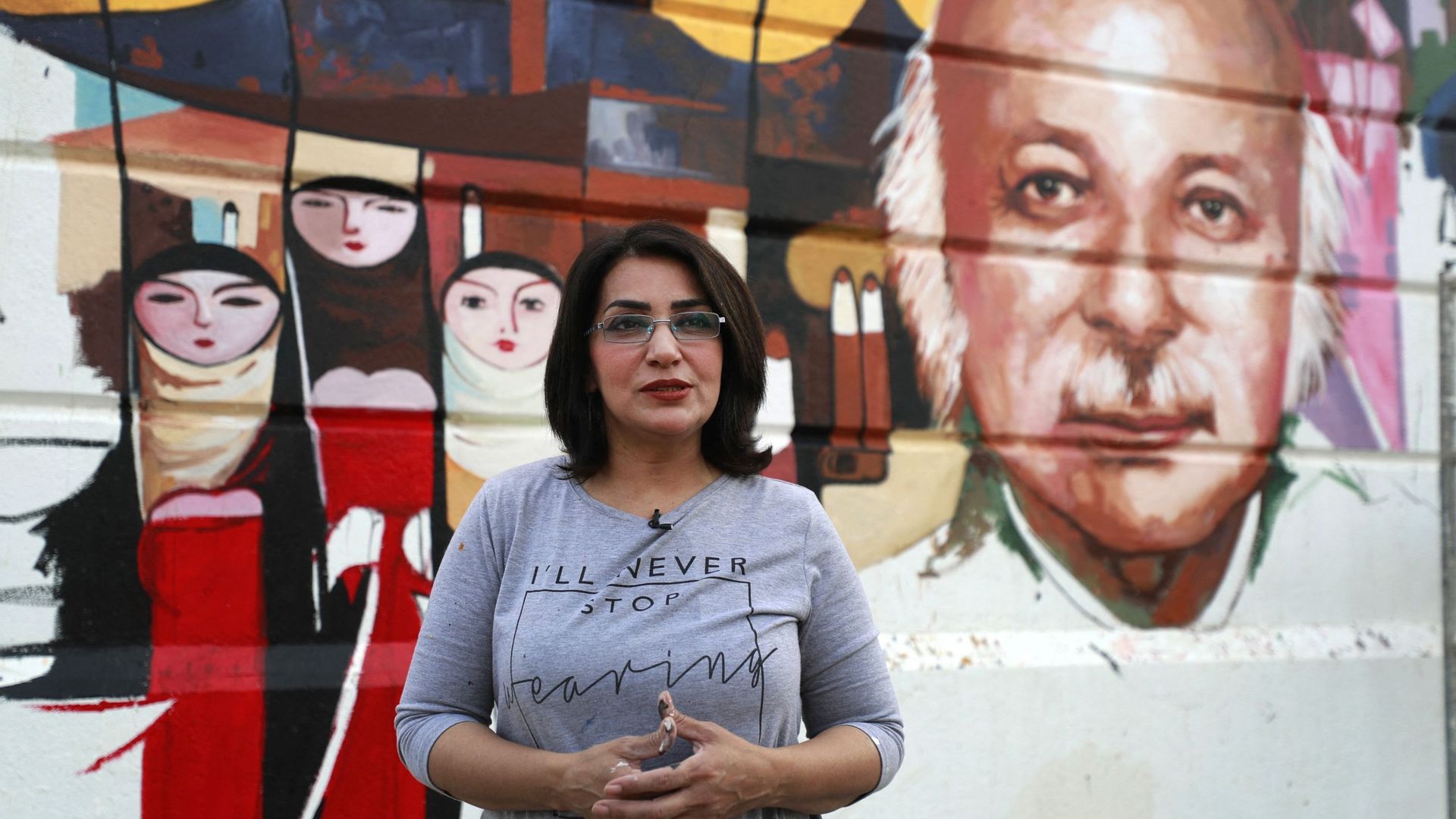 L’artiste irakienne Wijdan al-Majed devant son portrait mural du poète iraquien Muzzafar al-Nawab, peint dans une rue de Bagdad.