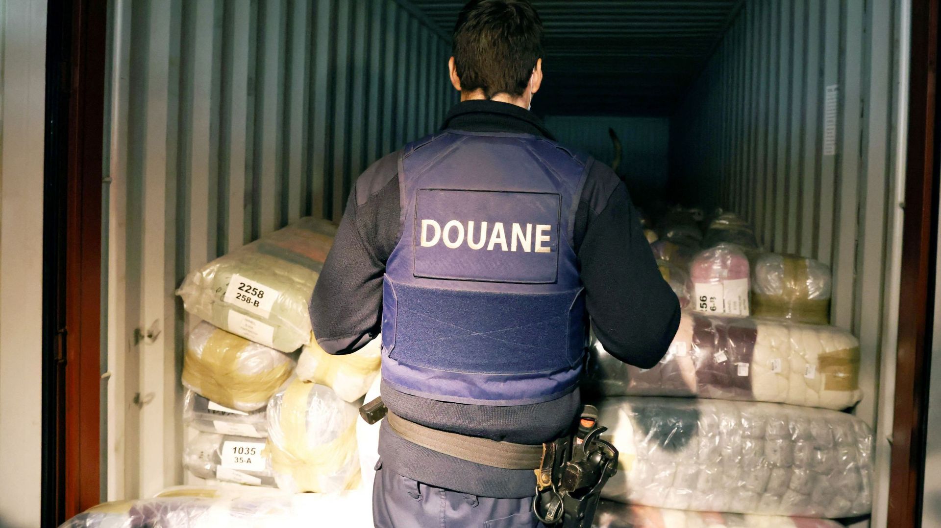 Des douaniers belges et un chien recherchent de la drogue dans un conteneur au port d'Anvers, le 7 janvier 2022.
