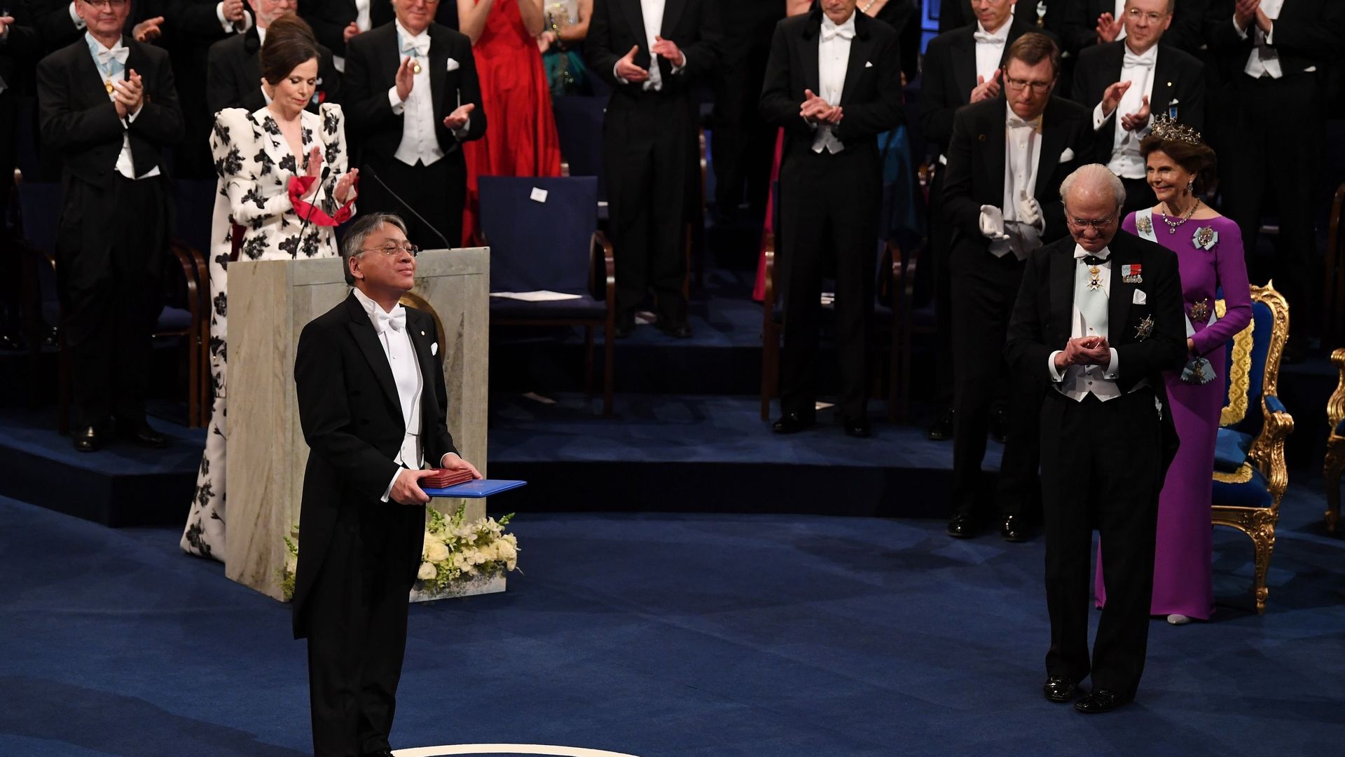 Kazuo Ishiguro, lauréat du prix Nobel de littérature reconnaît les applaudissements après avoir reçu son prix Nobel des mains du roi Carl XVI Gustaf de Suède lors de la cérémonie de remise des prix Nobel au Concert Hall le 10 décembre 2017 à Stockholm, en