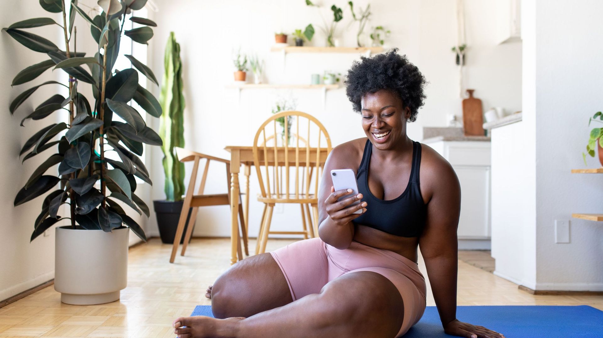 Woman using phone after exercising at home