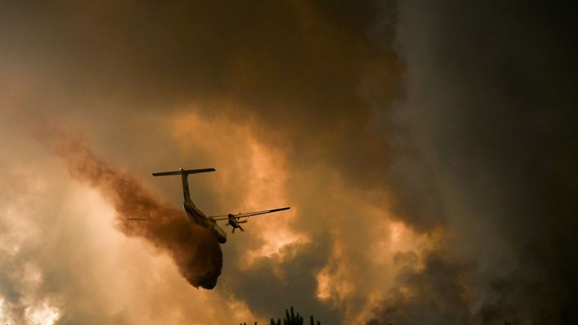Un avion pulvérise du retardateur de feu sur les arbres lors d'un incendie de forêt près de Belin-Beliet en Gironde, dans le sud-ouest de la France, le 10 août 2022