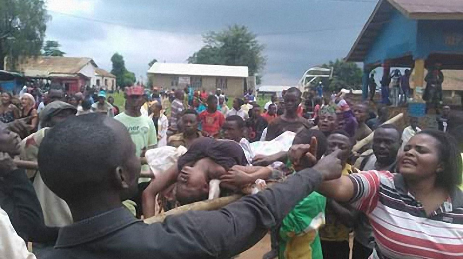 Des gens argumentent auprès d'une femme dont le corps est transporté à l'hôpital à Beni le 15 août 2016