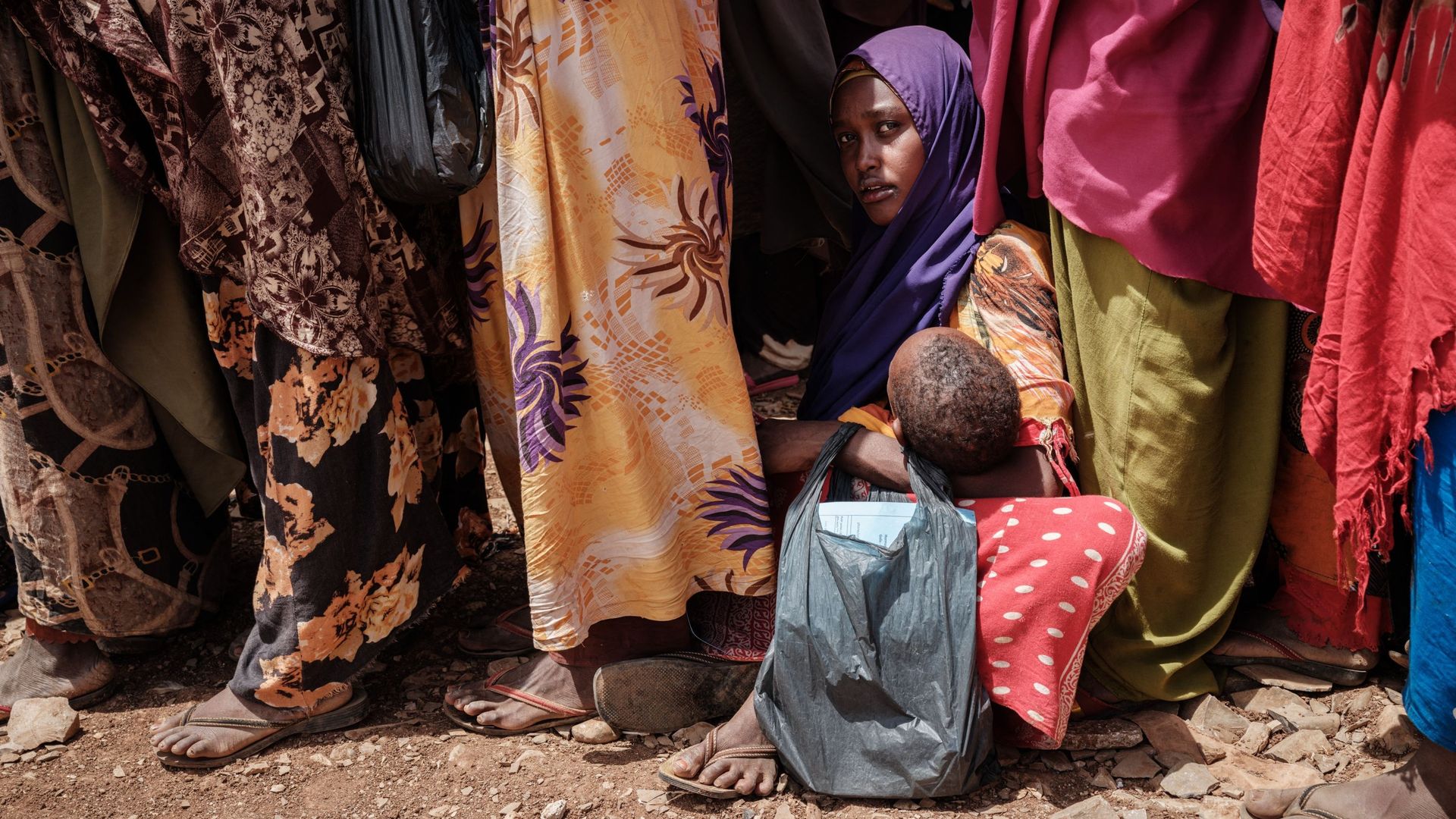 Une mère tient son enfant en attendant des aliments à haute valeur nutritive et des consultations médicales dans un camp à Baidoa, en Somalie, le 14 février 2022.