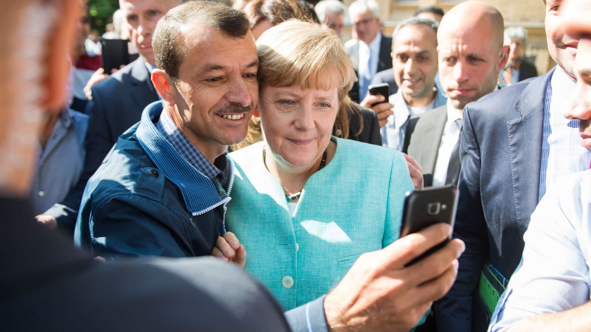 Un demandeur d'asile prend un selfie avec la chancelière allemande, Angela Merkel,  à la suite de sa visite dans une succursale de l'Office fédéral des migrations et des réfugiés et dans un camp de demandeurs d'asile à Berlin le 10 septembre 2015