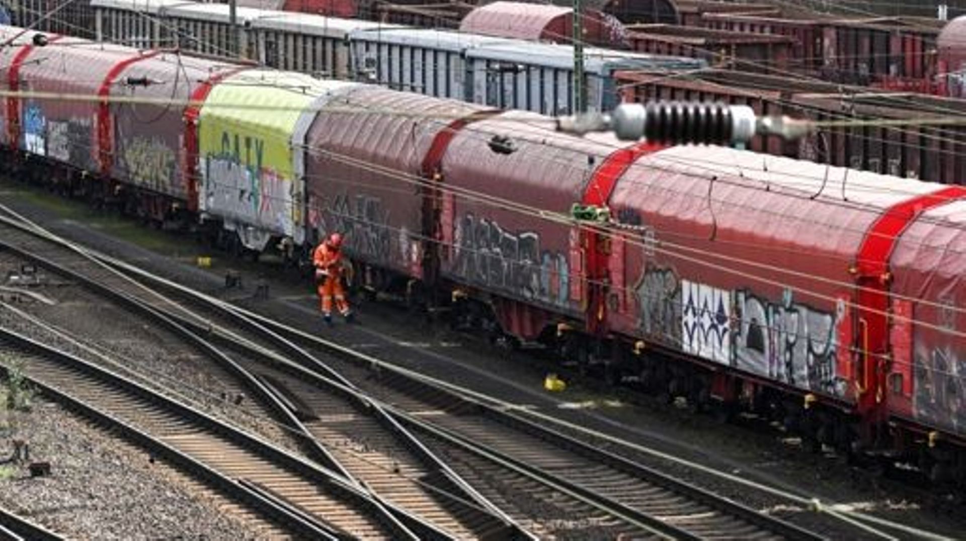 A worker walks past cargo wagons standing on train tracks of German railway operator Deutsche Bahn at the railway freight station in Hagen, western Germany, on March 24, 2023. Transport across much of Germany will be paralysed on Monday, March 27, 2023, a