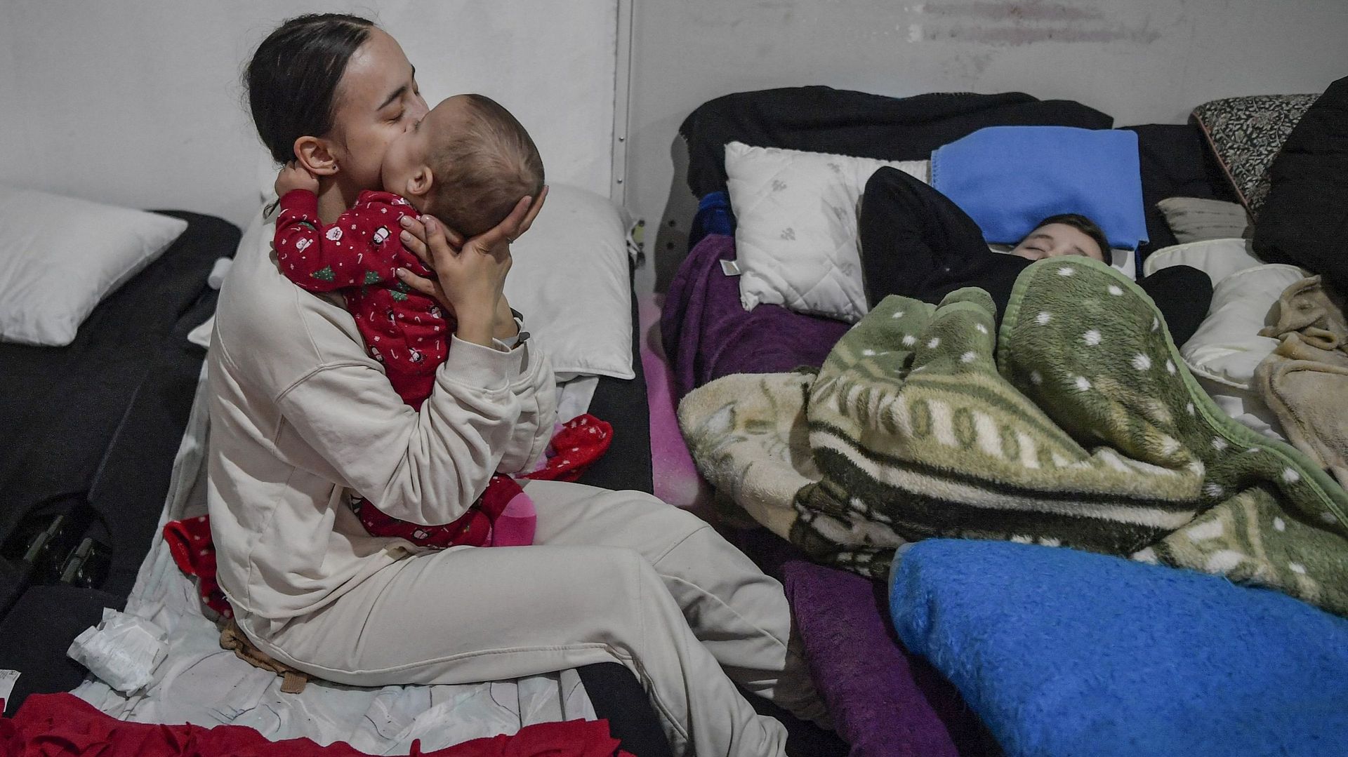 Une jeune mère réconforte son bébé dans un abri temporaire pour réfugiés ukrainiens, situé près de la frontière polono-ukrainienne dans un ancien centre commercial à Przemysl, en Pologne, le 8 mars 2022.