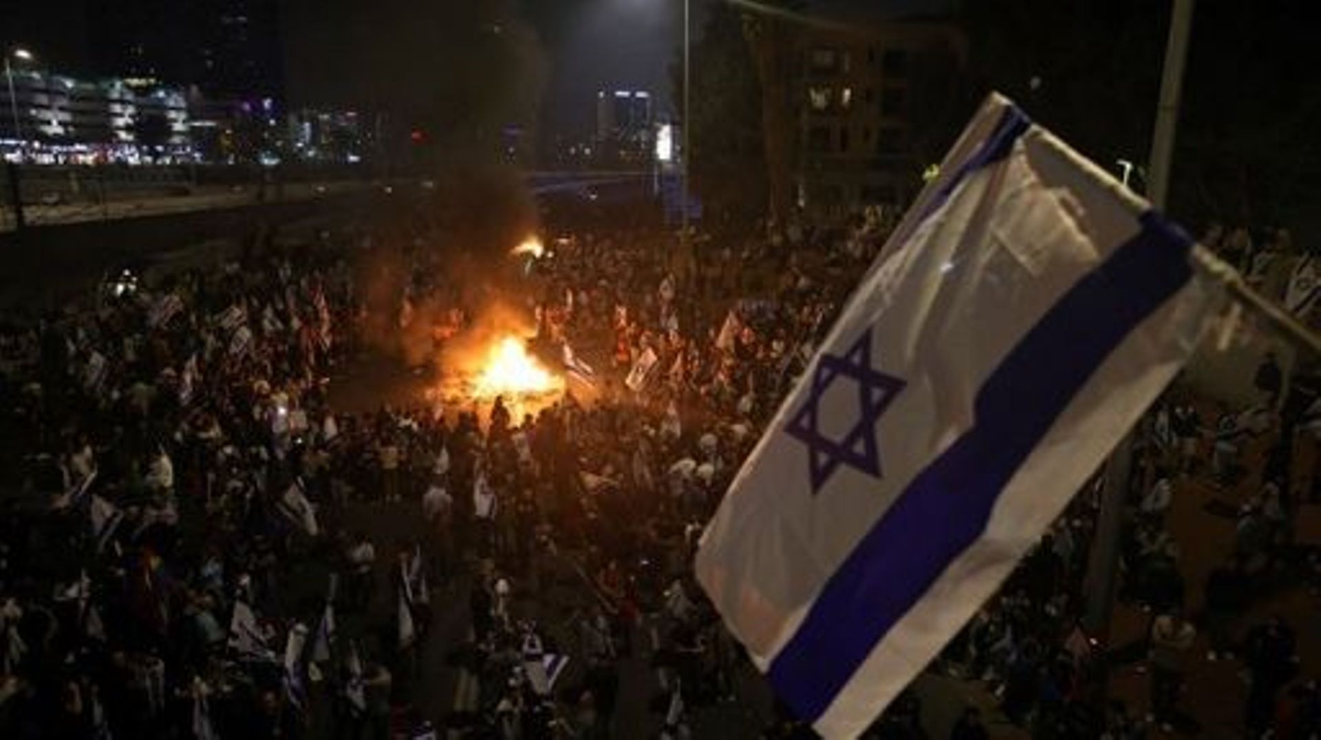 Protesters block a road and hold national flags as they gather around a bonfire during a rally against the Israeli government's judicial reform in Tel Aviv, Israel on March 27, 2023.  Israeli Prime Minister Benjamin Netanyahu on March 26, 2023 fired Defen