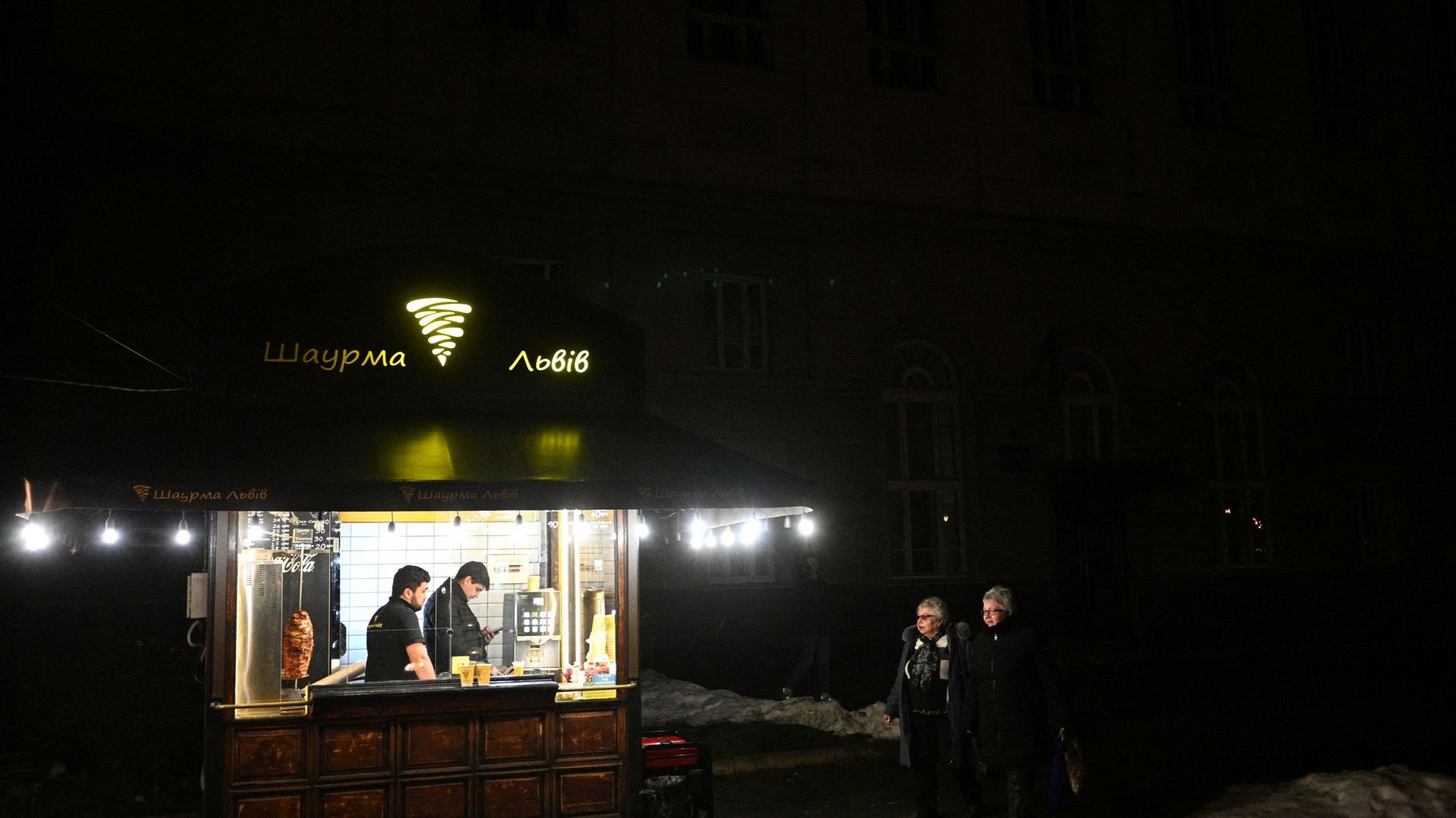 Des personnes passent devant un kiosque où l’électricité provient de générateurs électriques, dans le centre de la ville de Lviv, dans l’ouest de l’Ukraine, pendant la panne d’électricité, le 22 décembre 2022.