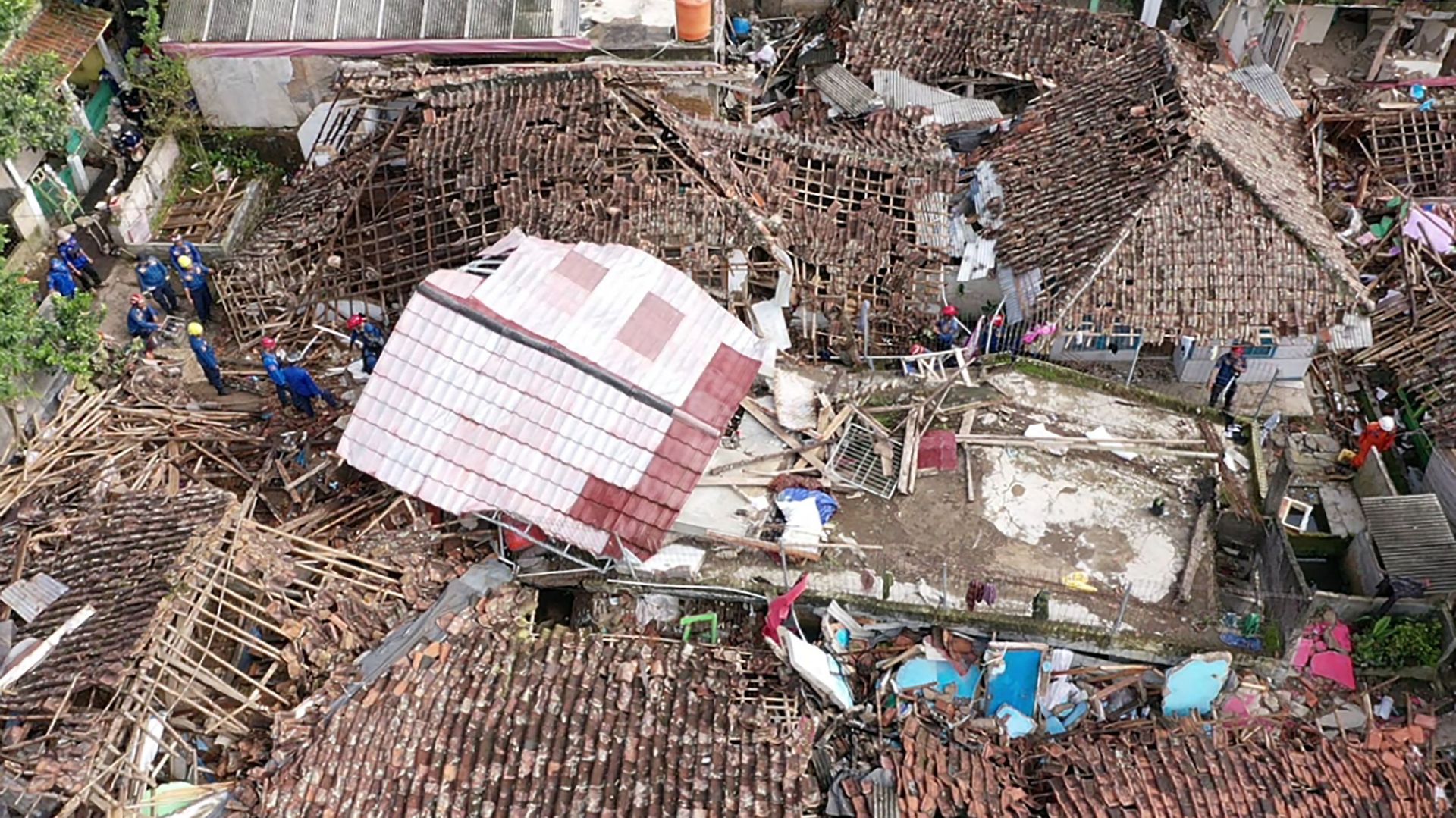 Une vue aérienne montre du personnel de secours travaillant à sauver un enfant des décombres d’une maison effondrée à Cugenang à Cianjur, Java Ouest, le 24 novembre 2022, suite au séisme de magnitude 5,6 survenu le 21 novembre.
