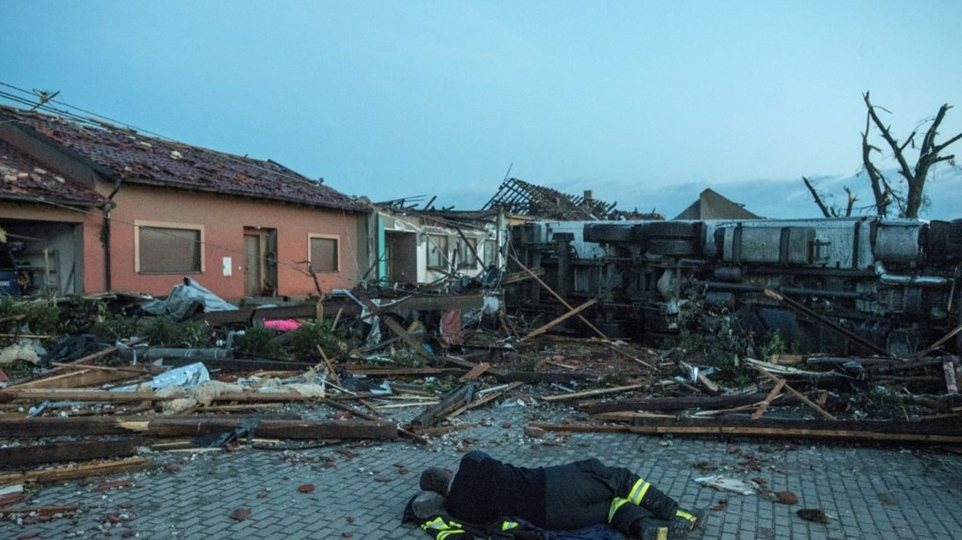 Un pompier se repose le 25 juin 2021 au petit matin dans une rue du village tchèque de Moravska Nova Ves, frappé par une tornade
