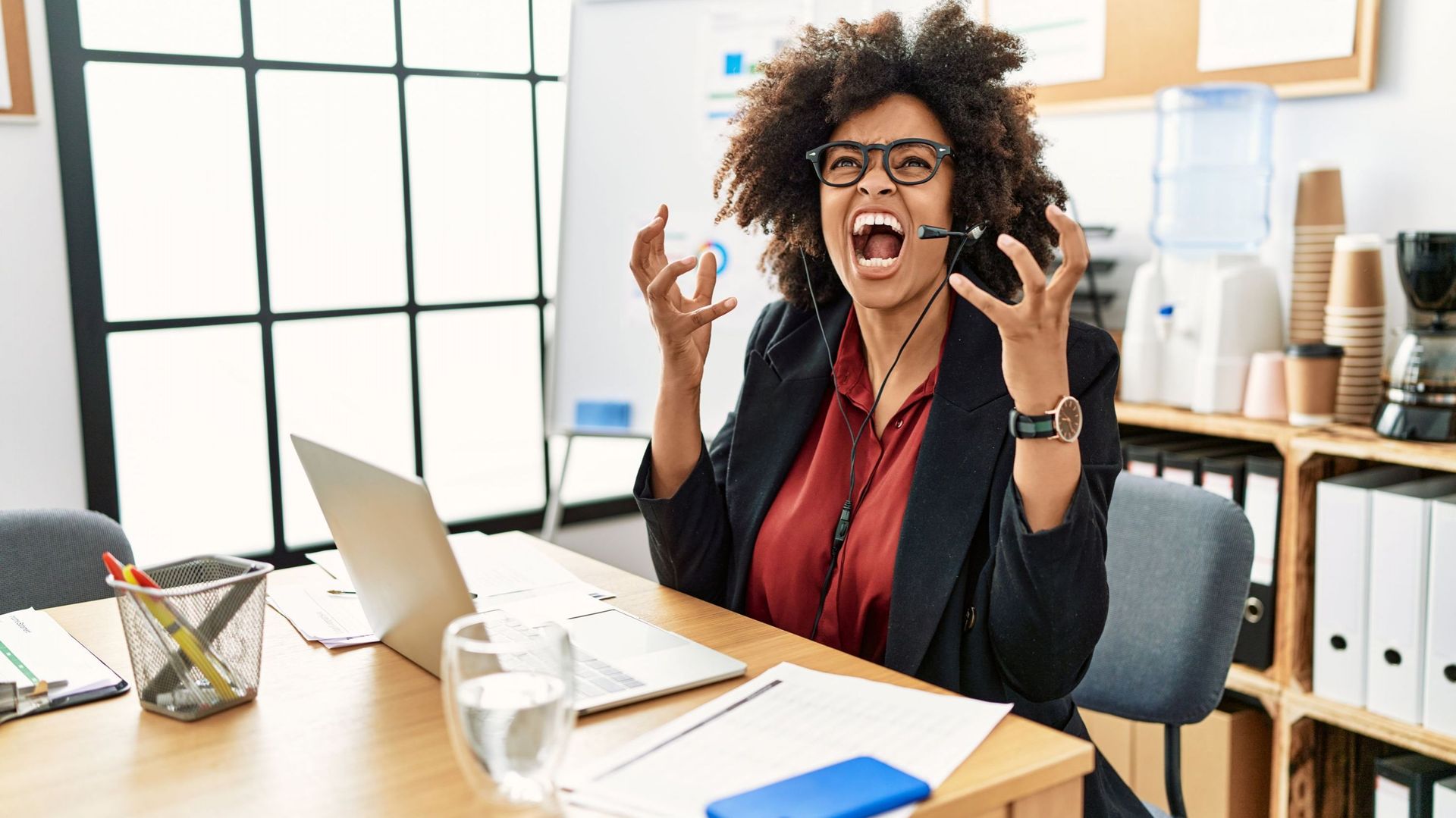 African american woman with afro hair working at the office wearing operator headset crazy and mad shouting and yelling with aggressive expression and arms raised. frustration concept.