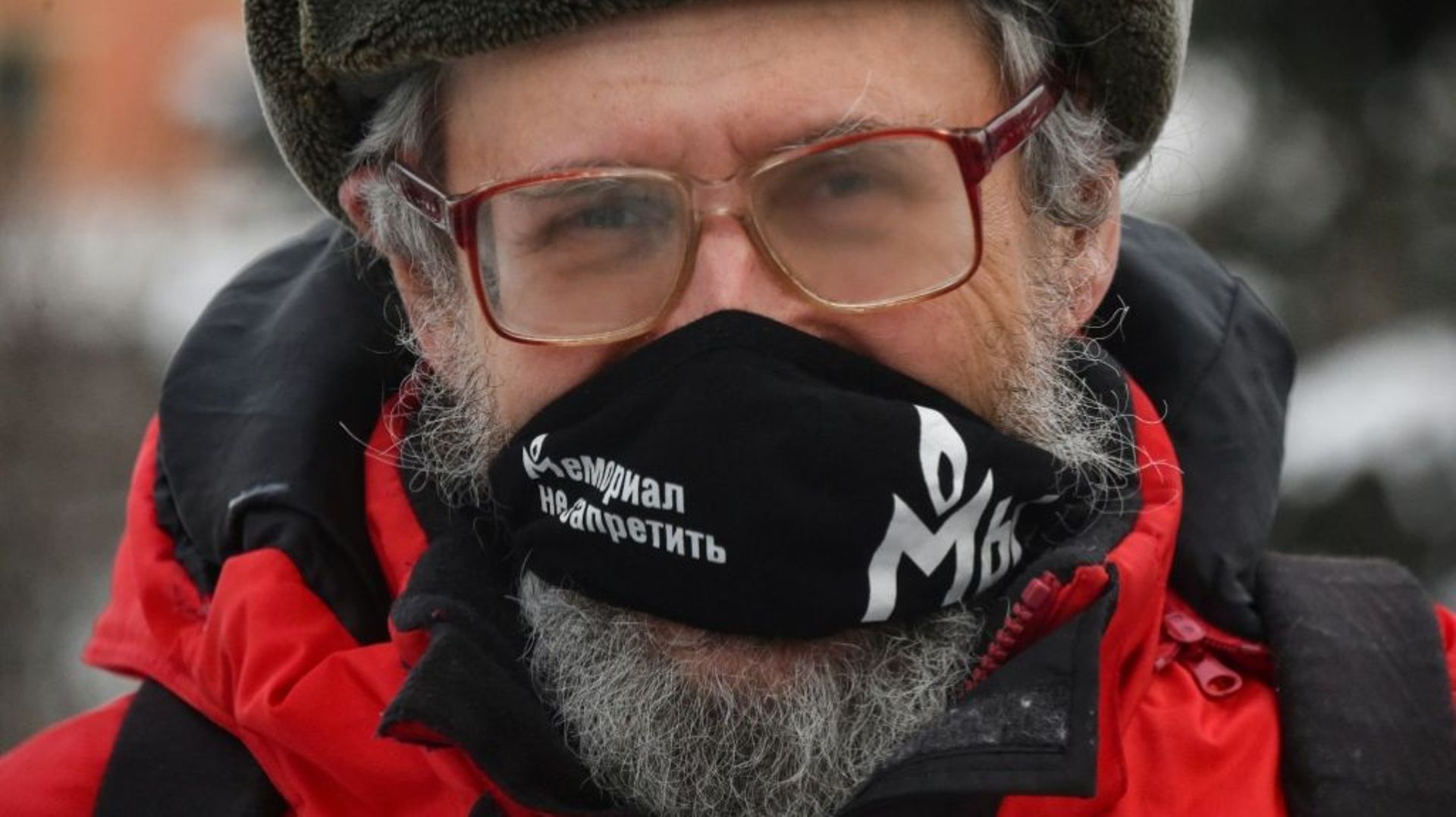 Un homme avec un masque à l’effigie de l’ONG russe de défense des droits humains Memorial devant le tribunal de Moscou, le 23 décembre 2021