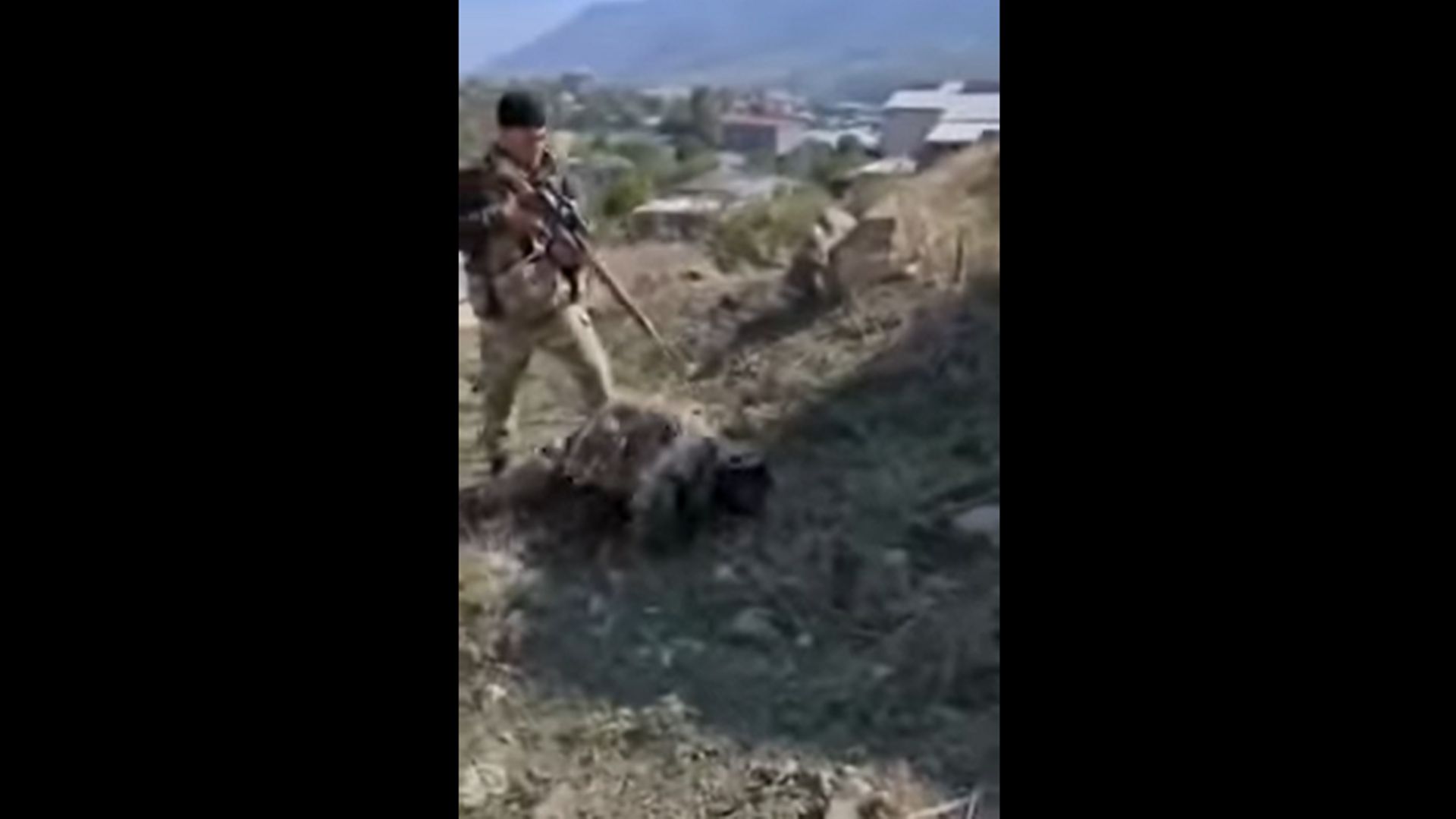 Un prisonnier arménien à terre, tenu en joue par un militaire azerbaïdjanais