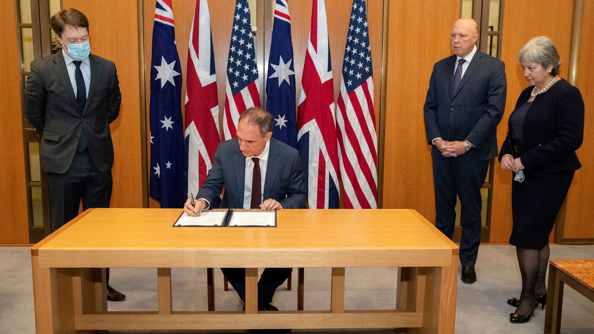Le Chargé d’Affaires américain Michael Goldman (2e G) signe l’accord d’échange d’informations sur la propulsion nucléaire navale sous le regard du Ministre australien de la Défense Peter Dutton (2e D) et du Haut-Commissaire britannique Victoria Treadell (