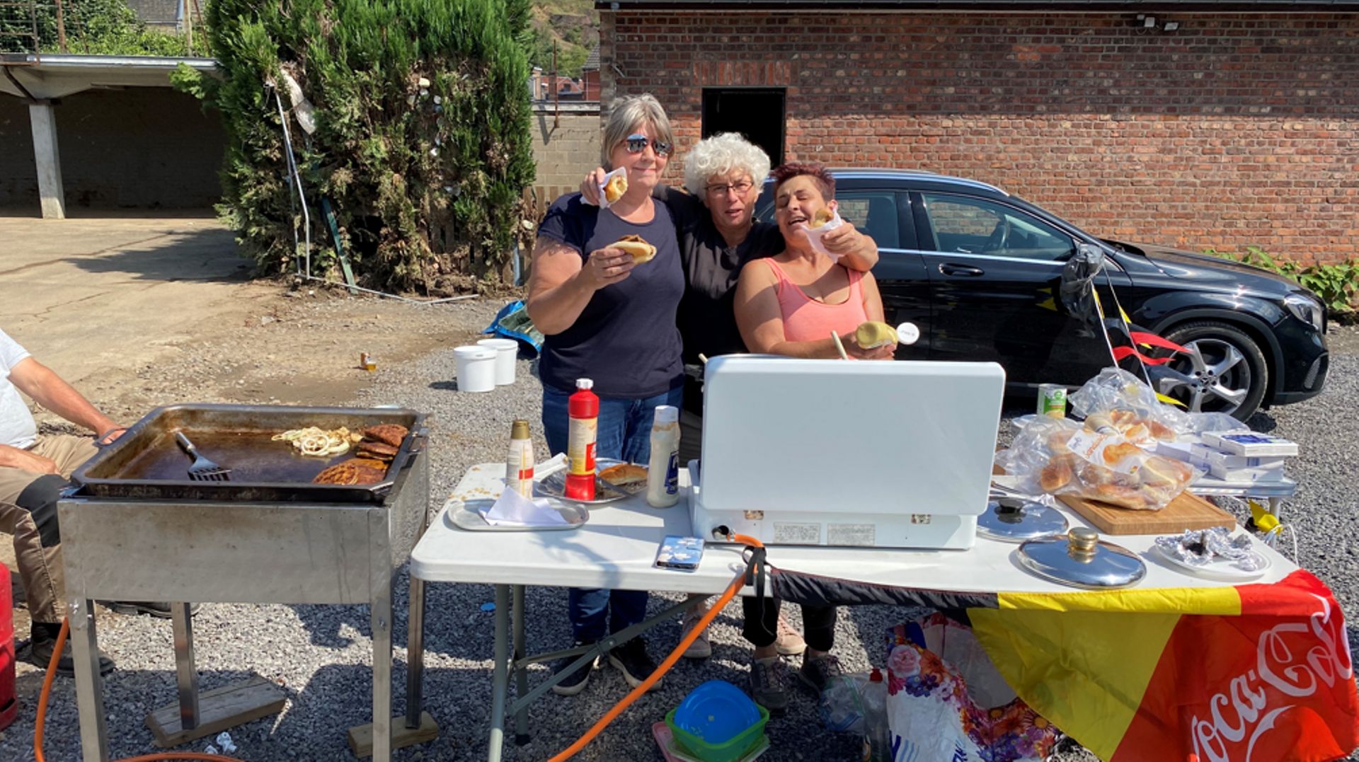 Une sinistrée entourée de deux bénévoles flamandes, dont Christina, à droite, qui fait des hot dogs.