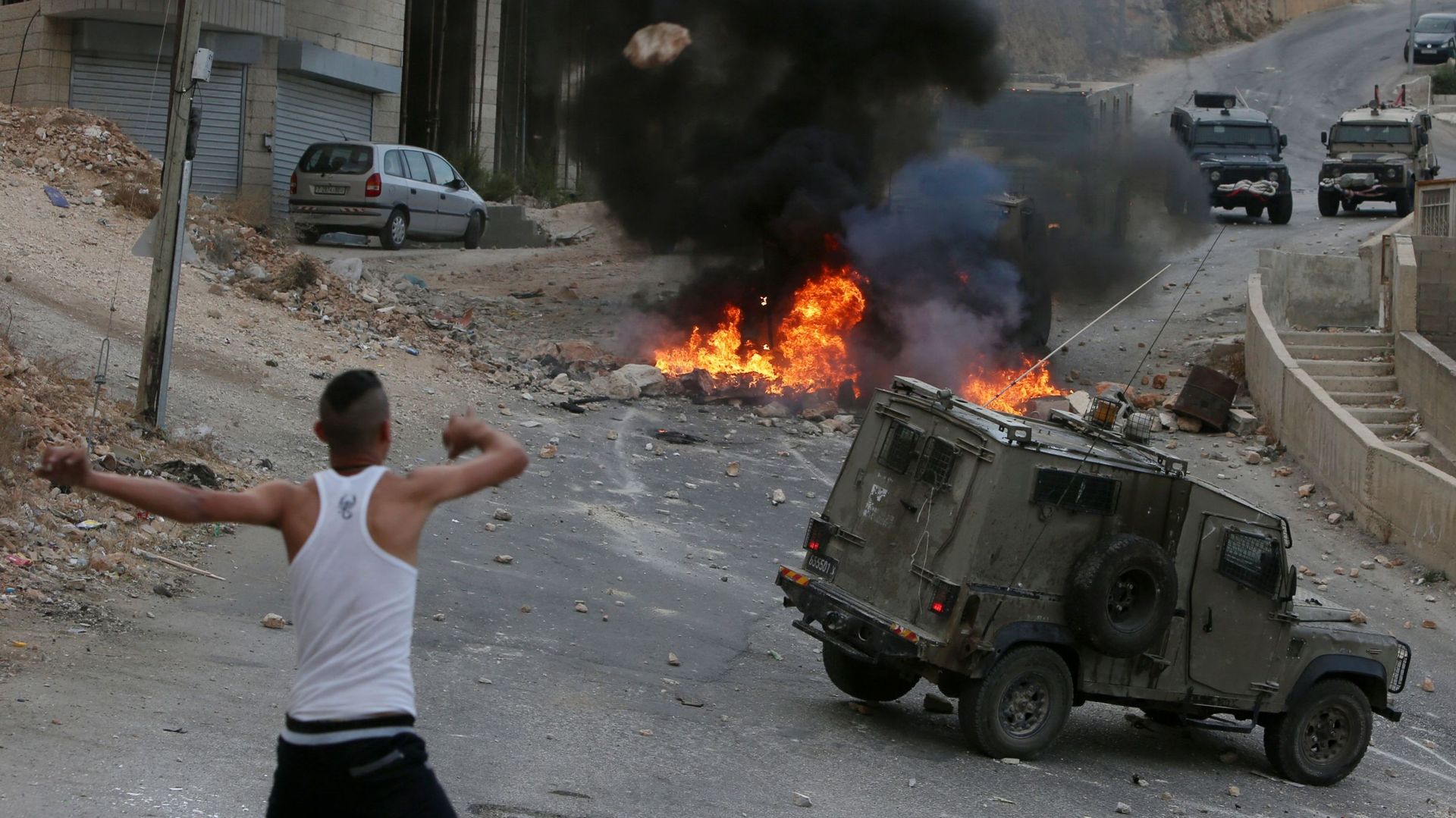 Un jeune Palestinien lance une pierre en direction d'un véhicule des forces israéliennes, à Naplouse, en Cisjordanie occupée.