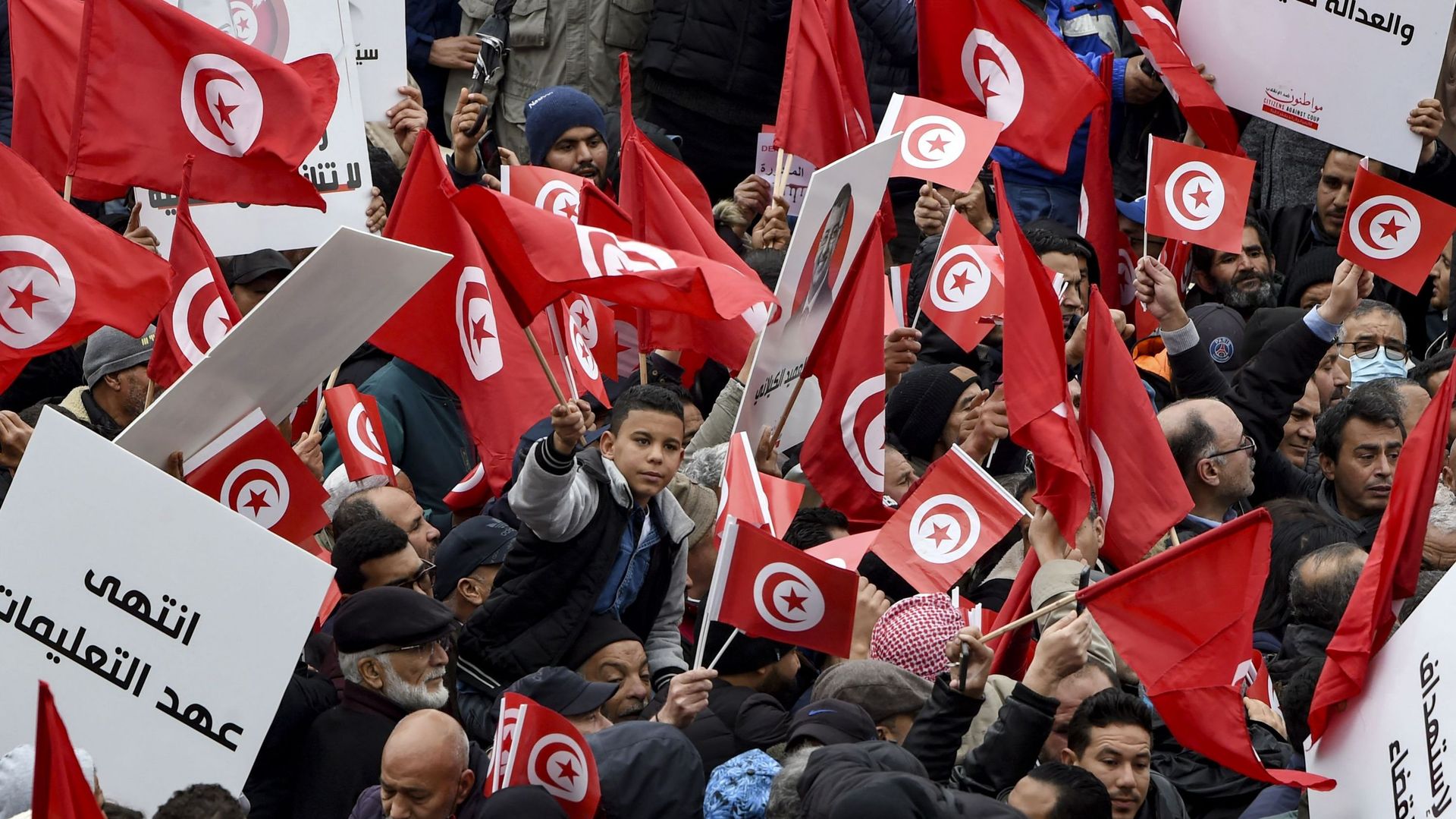 Des manifestants tunisiens brandissent des pancartes et des drapeaux nationaux lors d’une manifestation contre leur président, non loin du siège de l’Assemblée tunisienne (parlement), dans la capitale Tunis, le 20 mars 2022.
