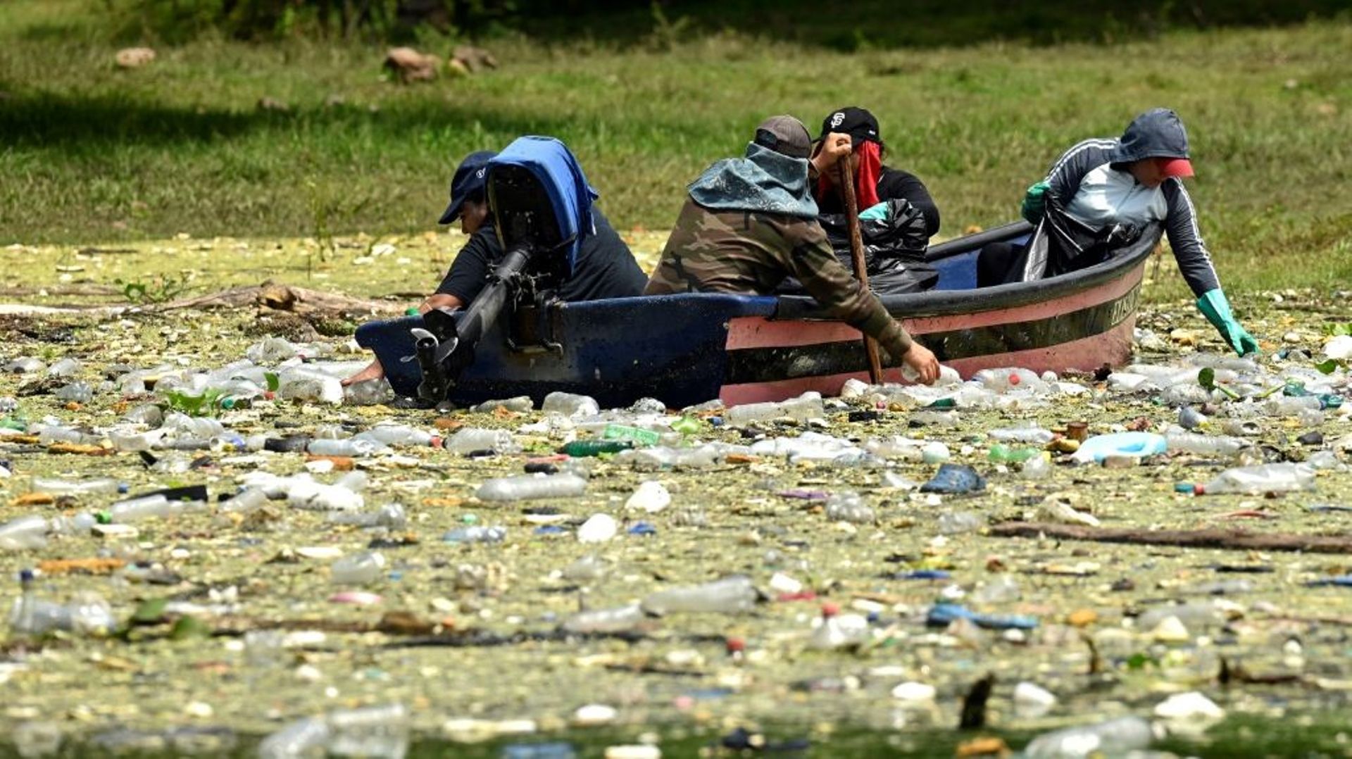 Des habitants ramassent des déchets plastiques et autres flottant à la surface du réservoir Cerron Grande à Potonico, le 9 septembre 2022 au Salvador