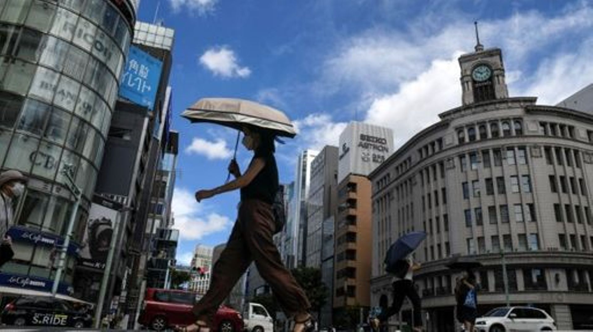 Des piétons utilisent des parapluies pour s'abriter du soleil dans le quartier de Ginza à Tokyo, le 11 août 2022, alors que des températures de 36 degrés centigrades (98F) sont revenues dans la région (illustration)