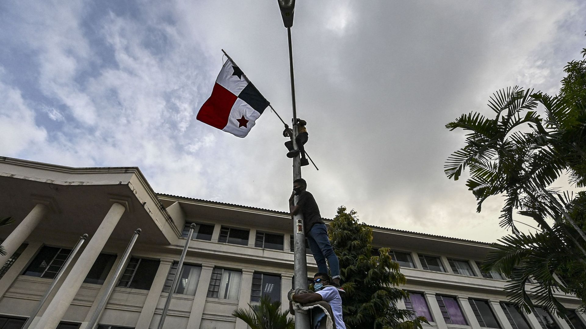 Des hommes escaladent un lampadaire avec un drapeau panaméen lors d’une manifestation contre le mariage homosexuel, devant la Cour suprême de justice, à Panama, le 7 octobre 2020.